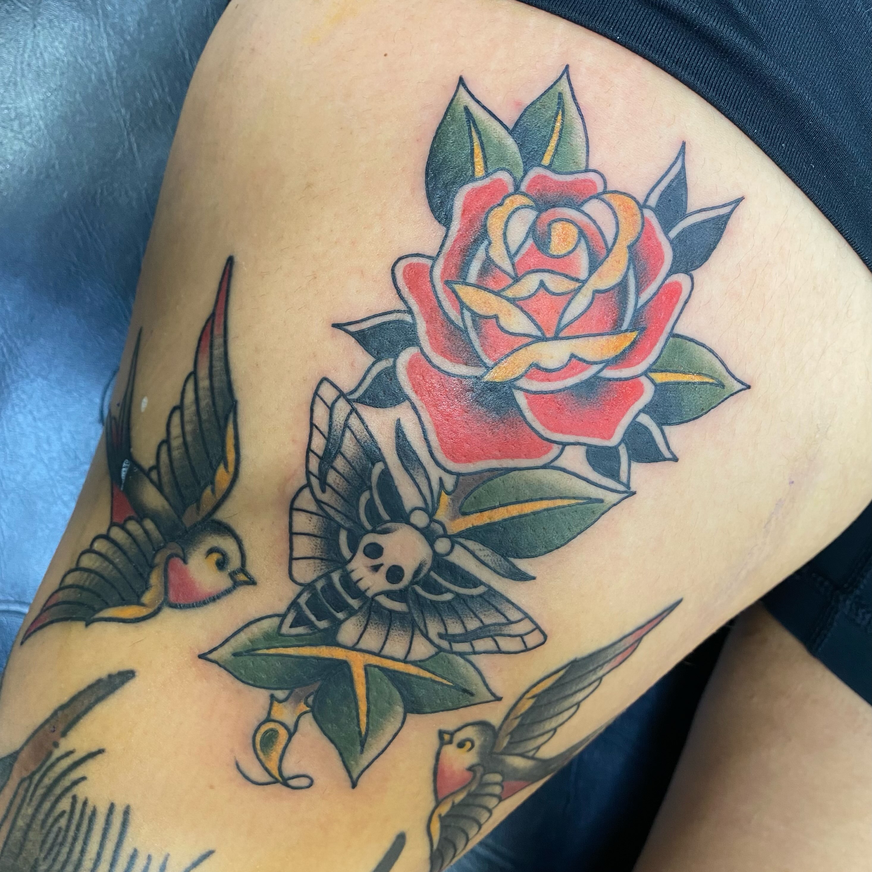 Rose and moth American traditional tattoo on the thigh by Jarid Penn