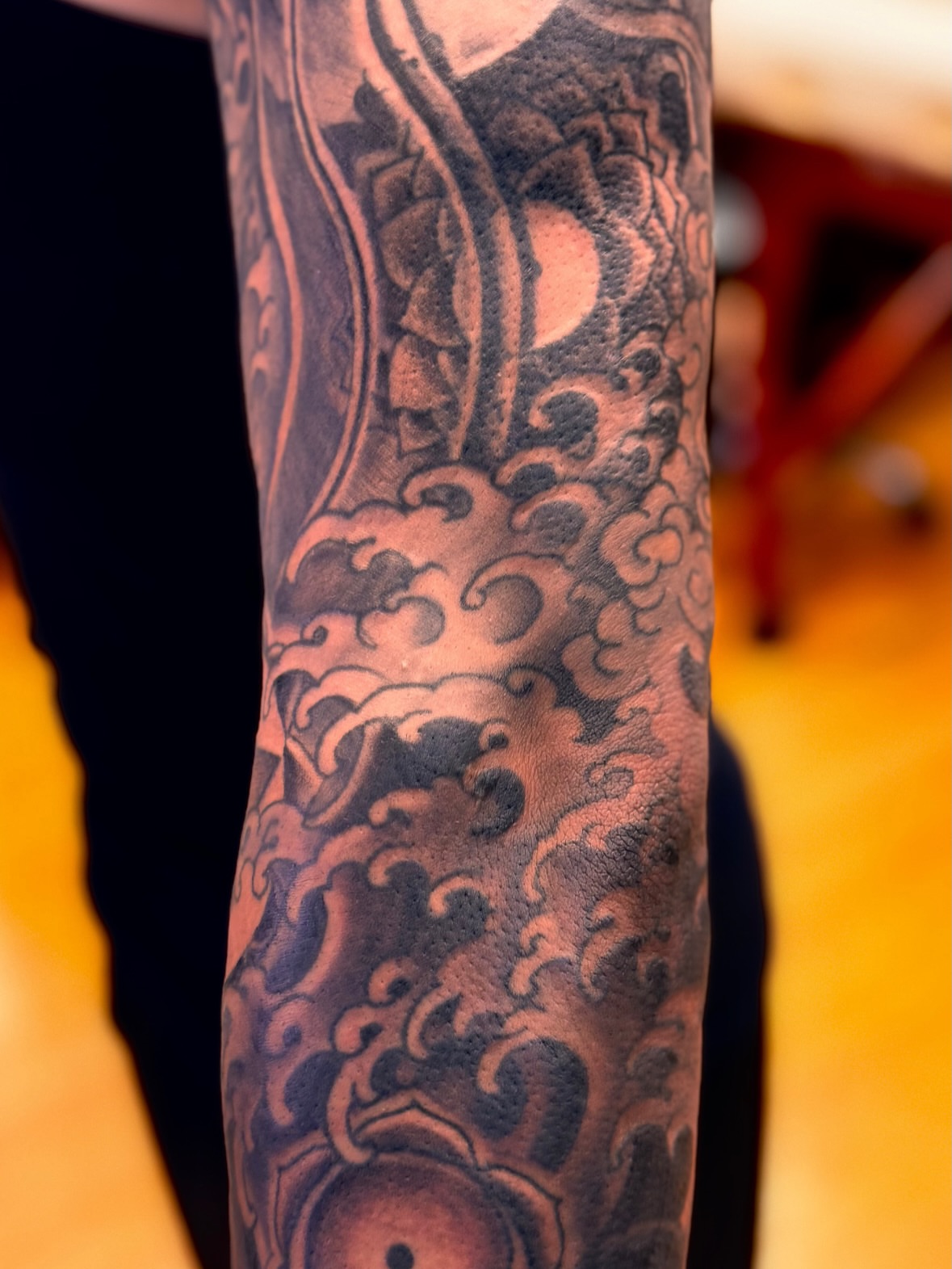 Wave and sun black and grey tattoo on the forearm by Brian Hutflies