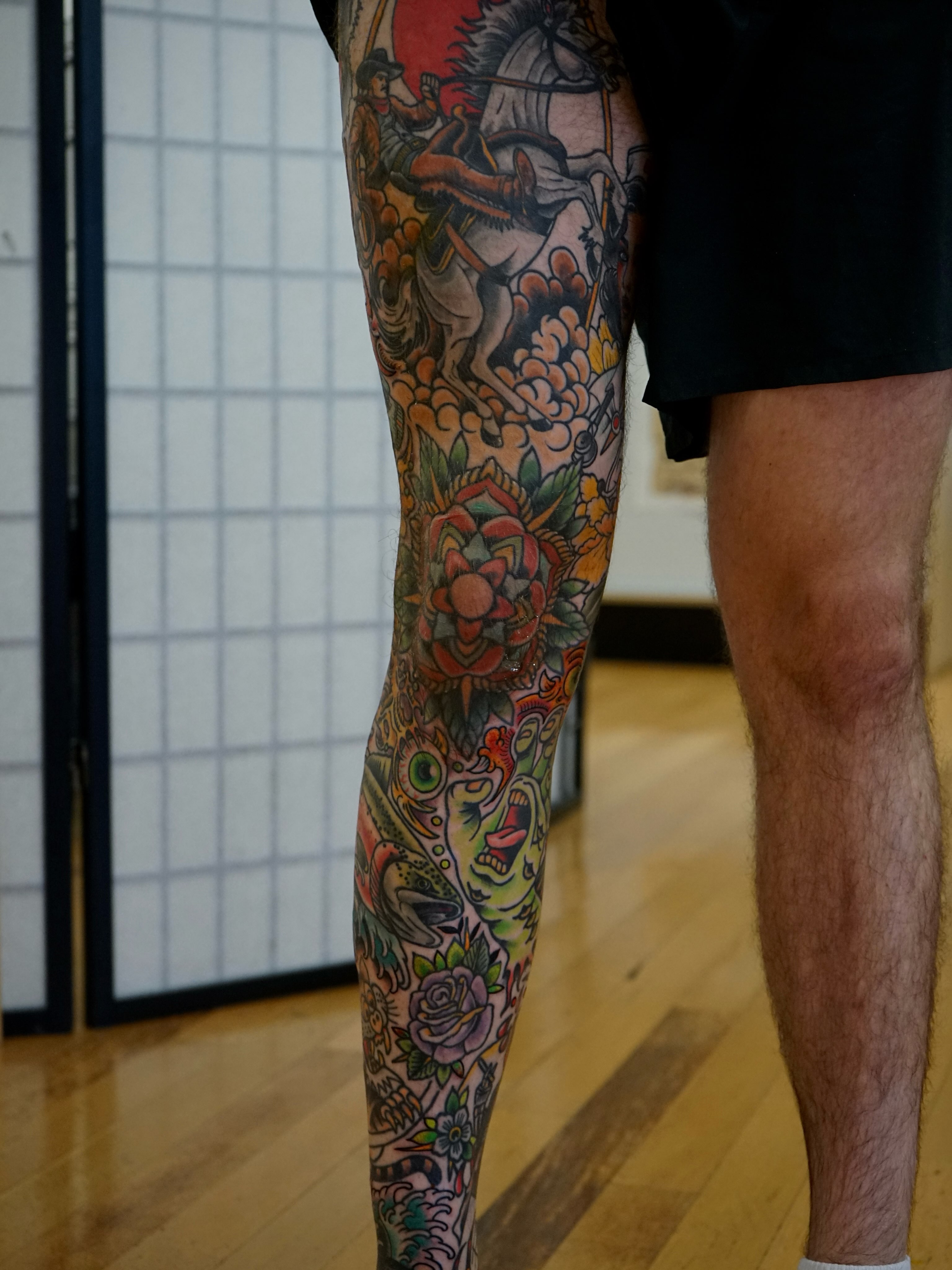 Horse rider and floral American traditional tattoo on the leg by Tyler Harrington
