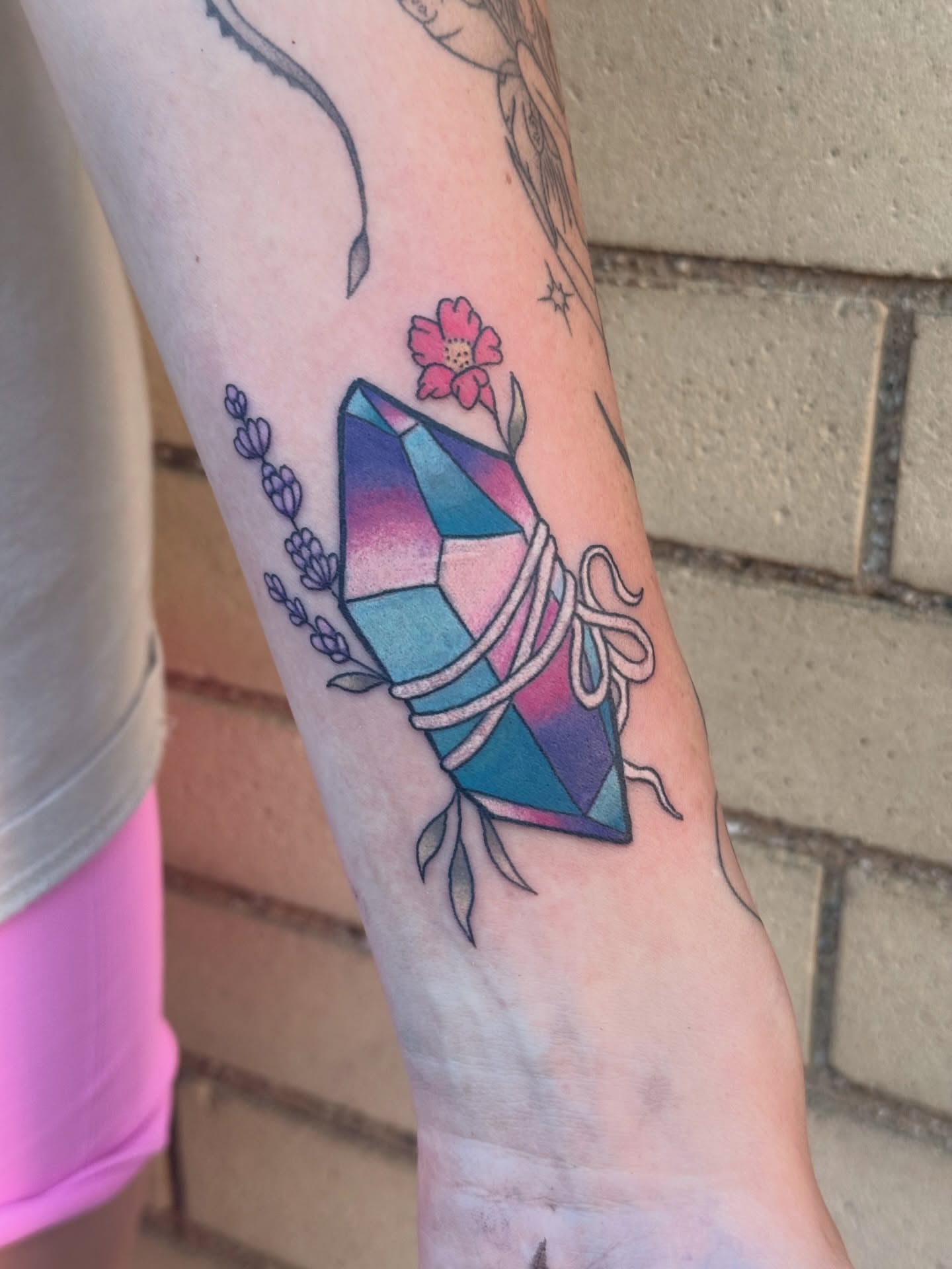 Gemstone with flowers geometric tattoo on the forearm by Mo