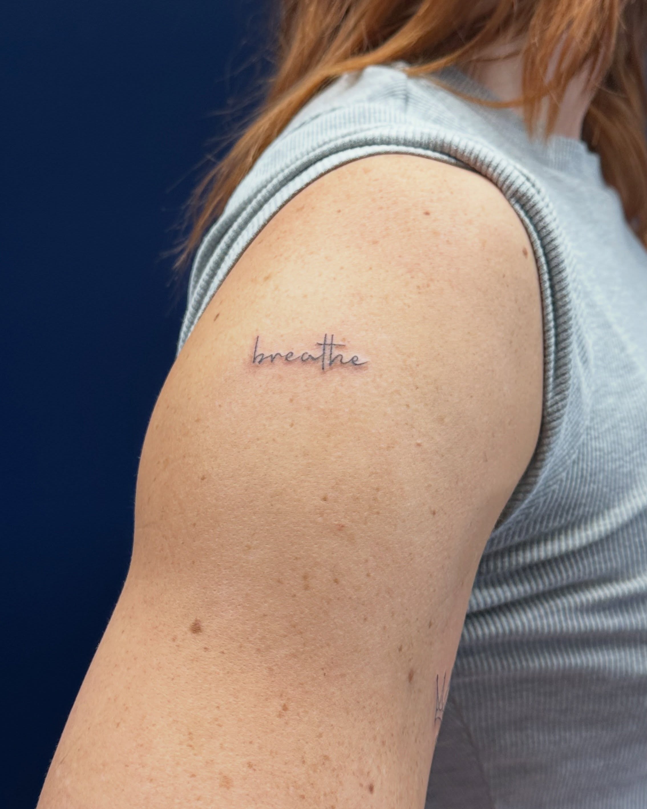 Breathe lettering script tattoo on the shoulder by Tattoo Takayo