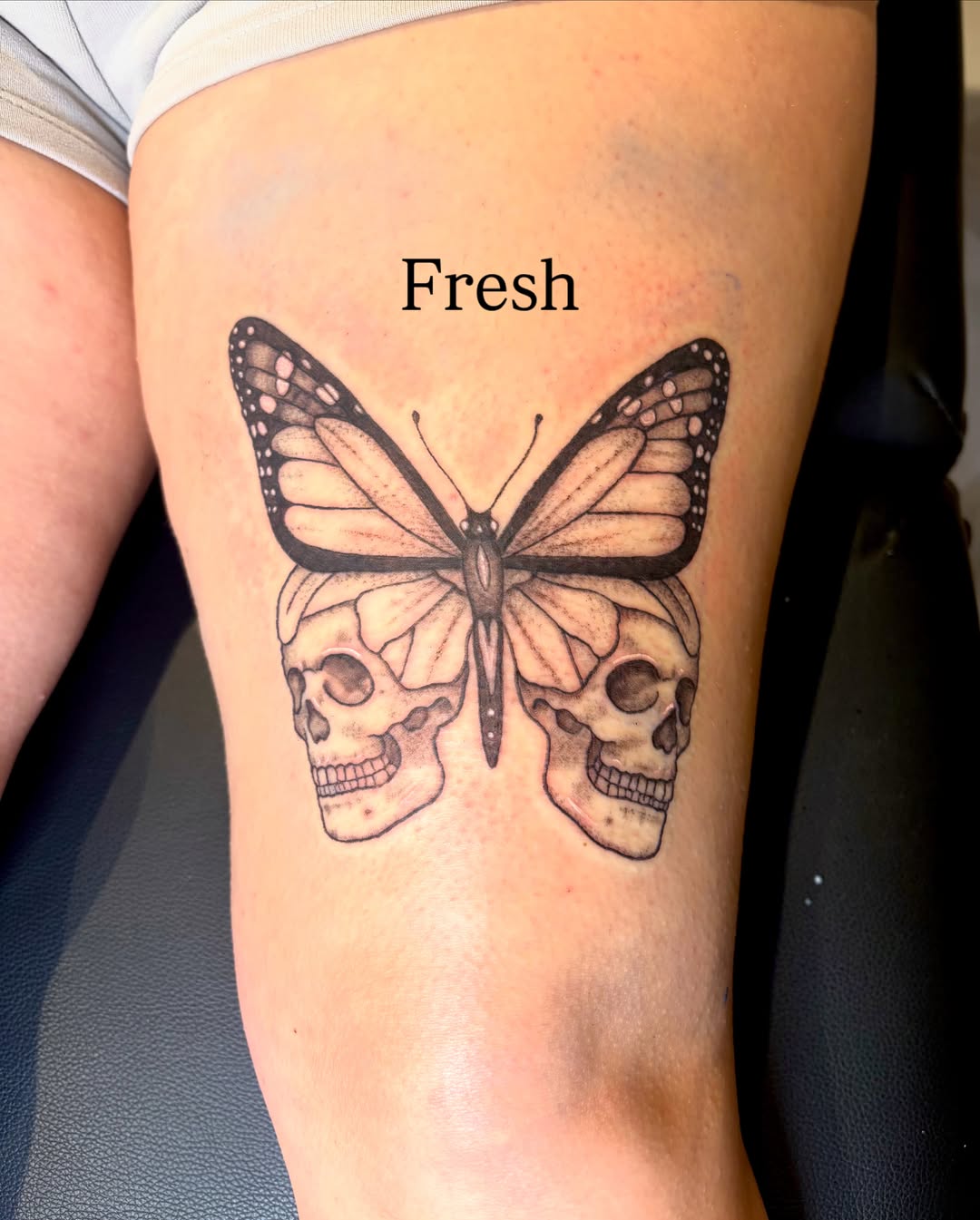 Butterfly and skulls black and grey tattoo on the thigh by Emily, Monticello, Iowa