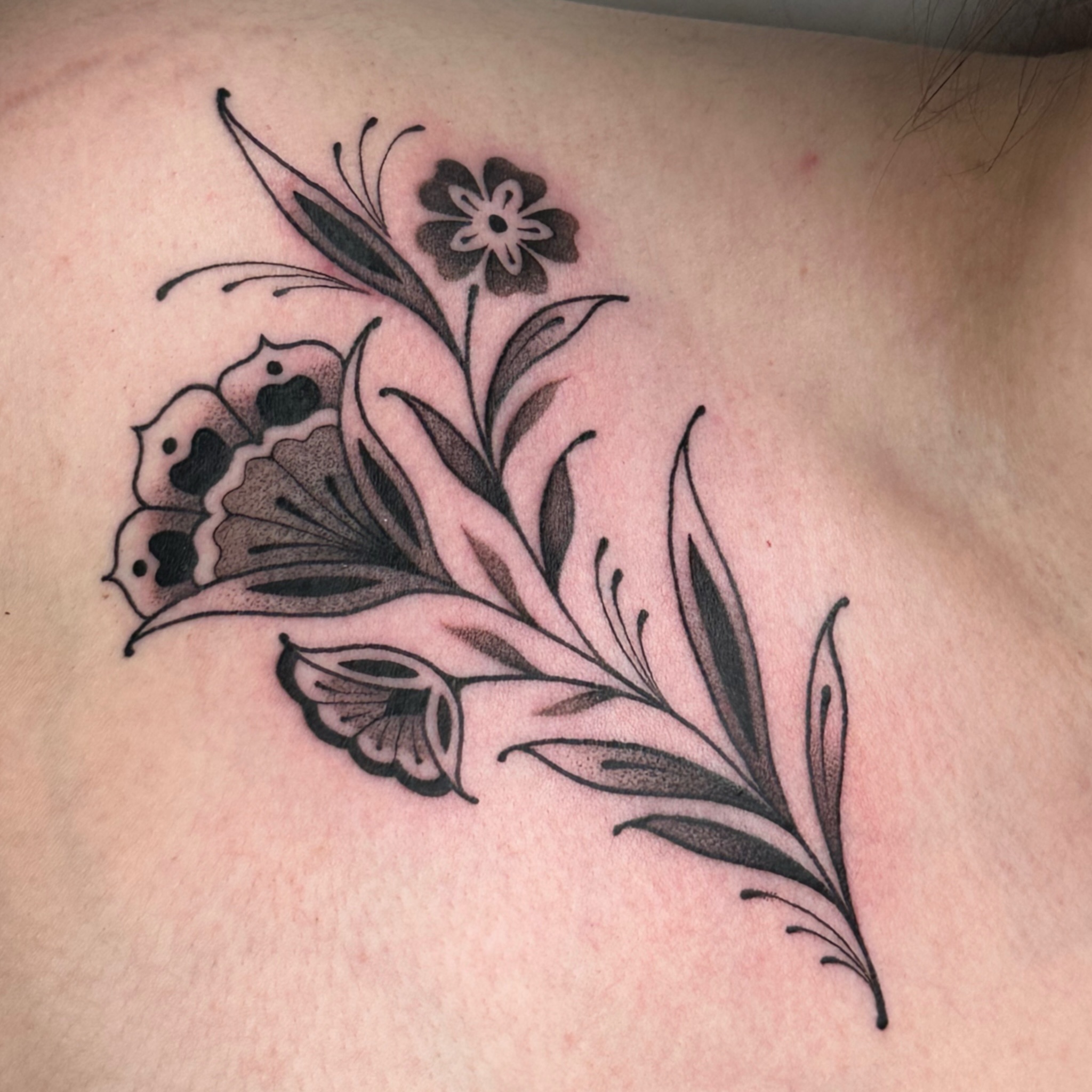 Floral arrangement black and grey tattoo on the back by kira