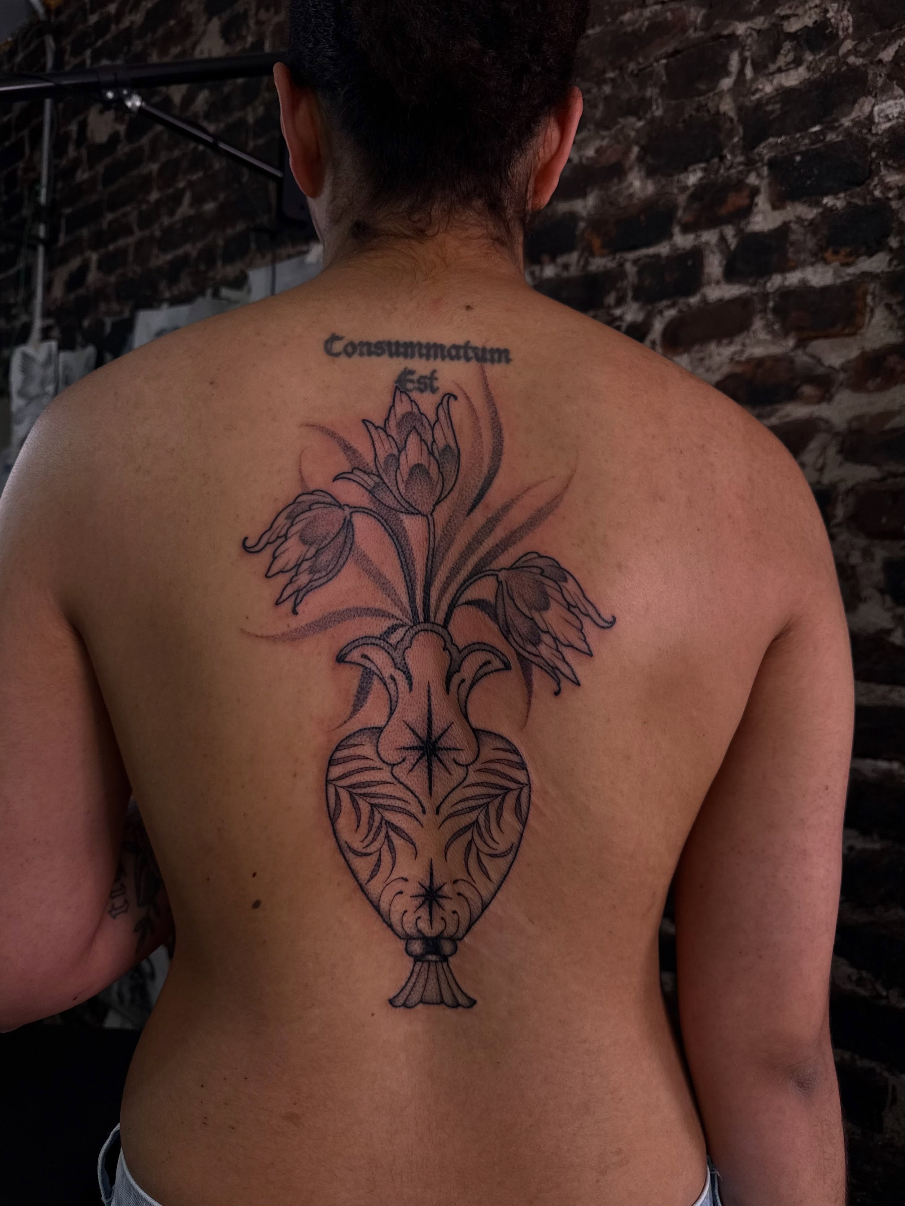 Vase with flowers black and grey tattoo on the back by Erin Shea