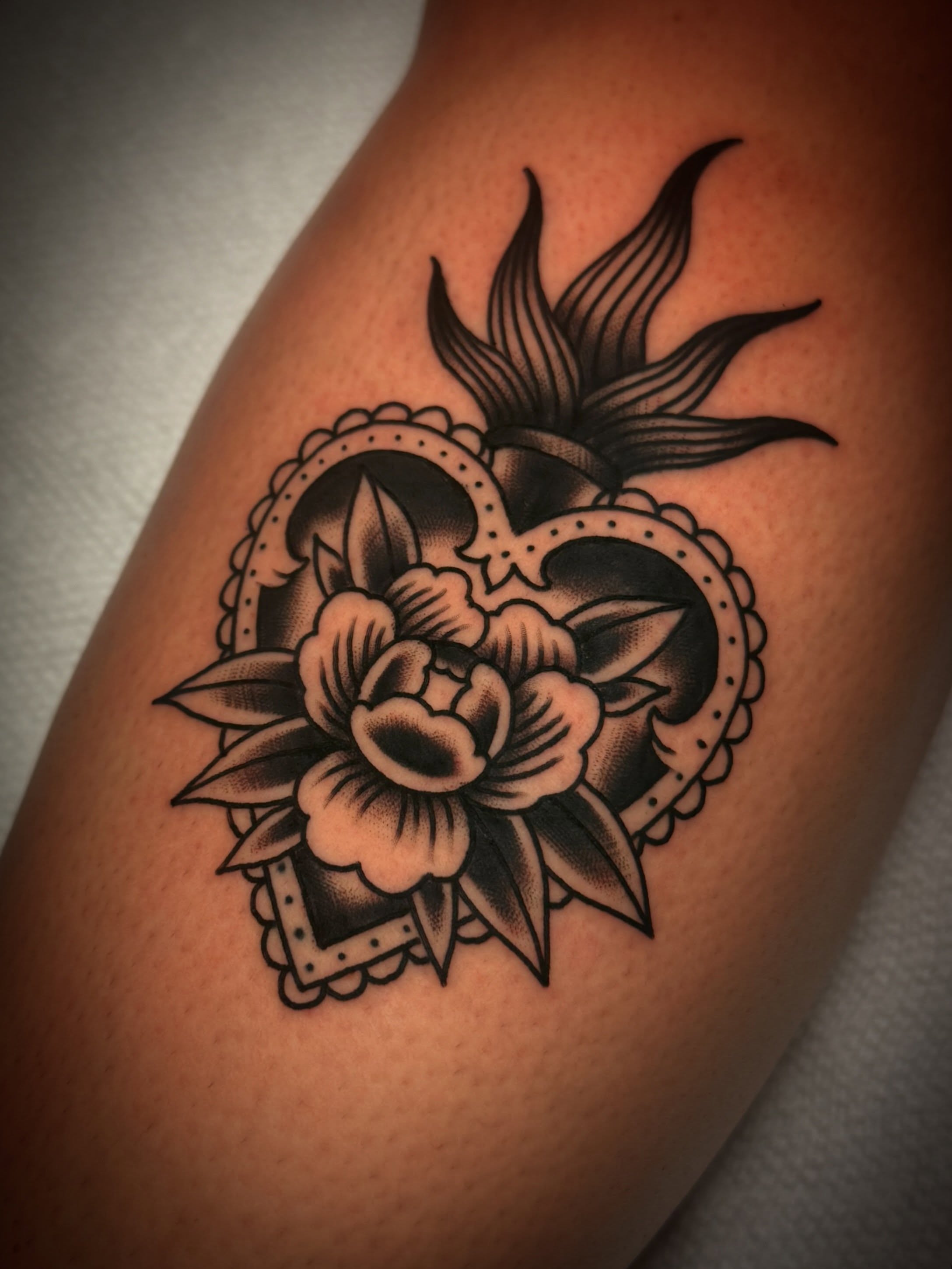 Heart with floral ornament American traditional tattoo on the thigh by Dave Osrowitz