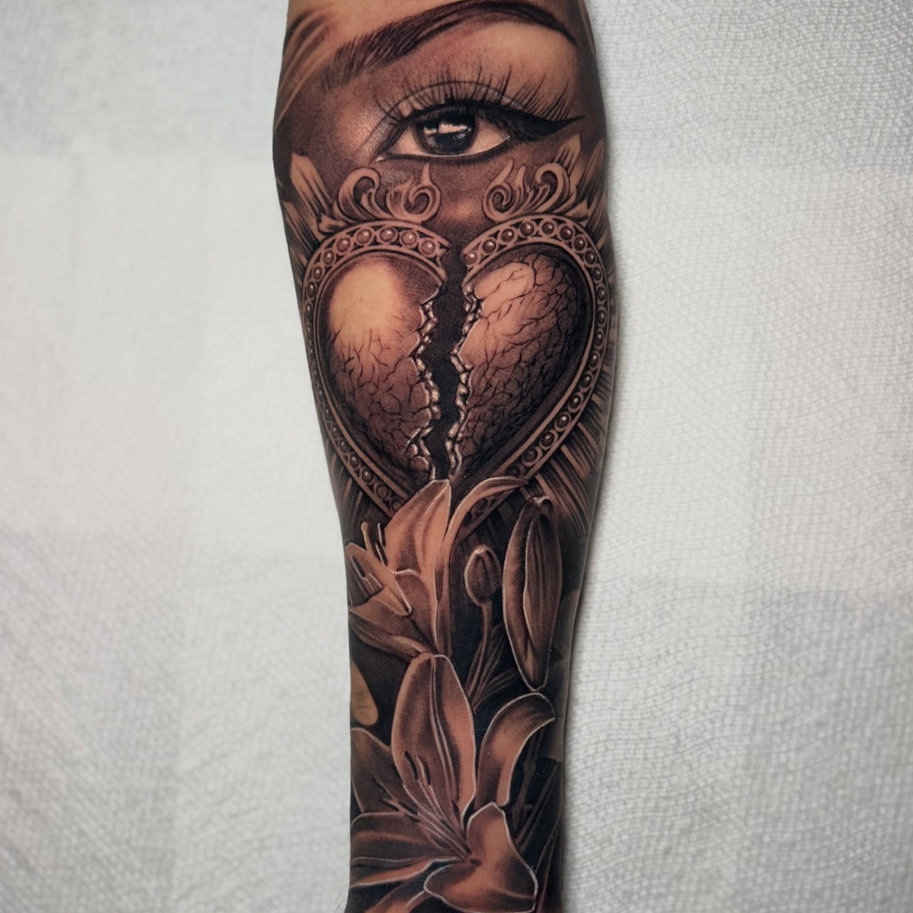 Broken heart with woman's eye dark realism tattoo on the forearm by Flames, Cerritos, California