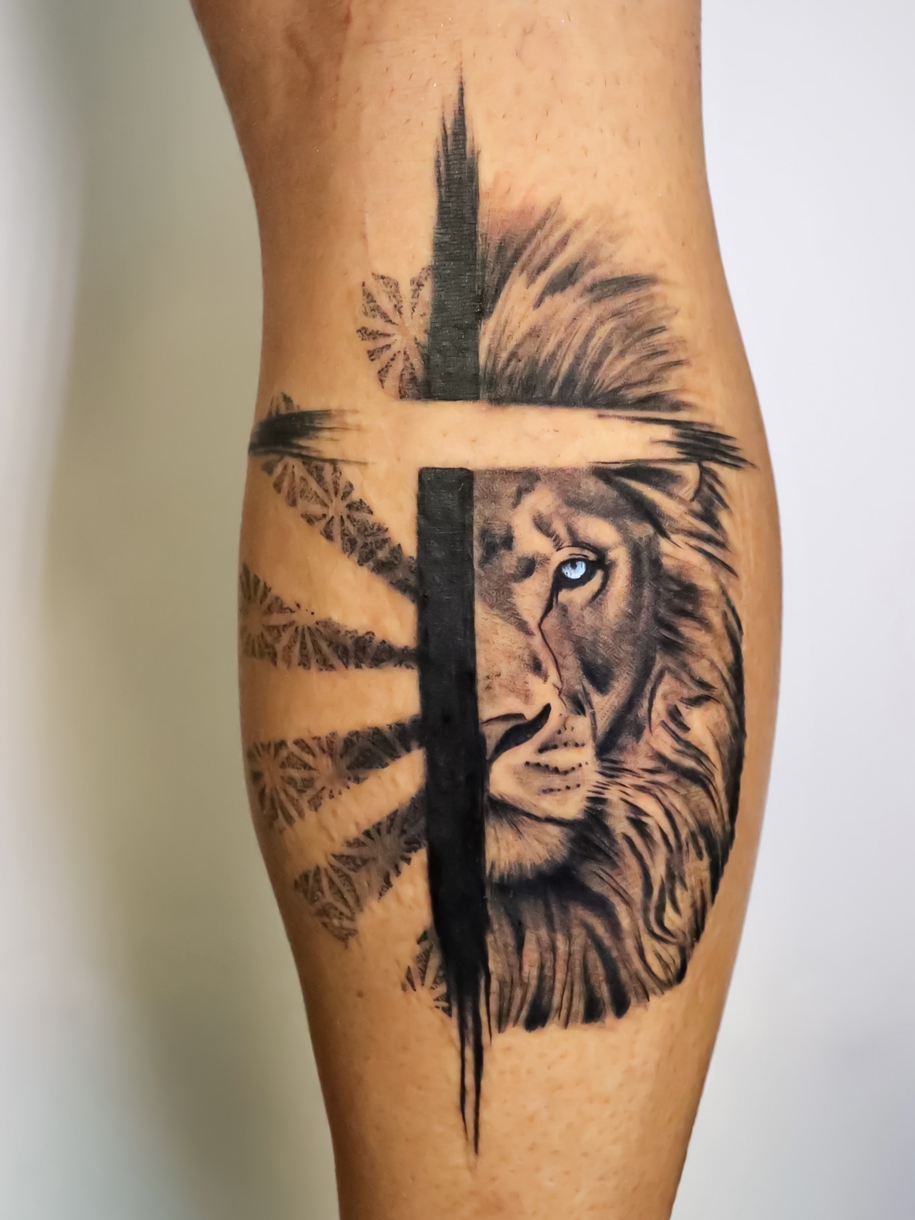 Lion and cross realism tattoo on the forearm by Angel Tattoos