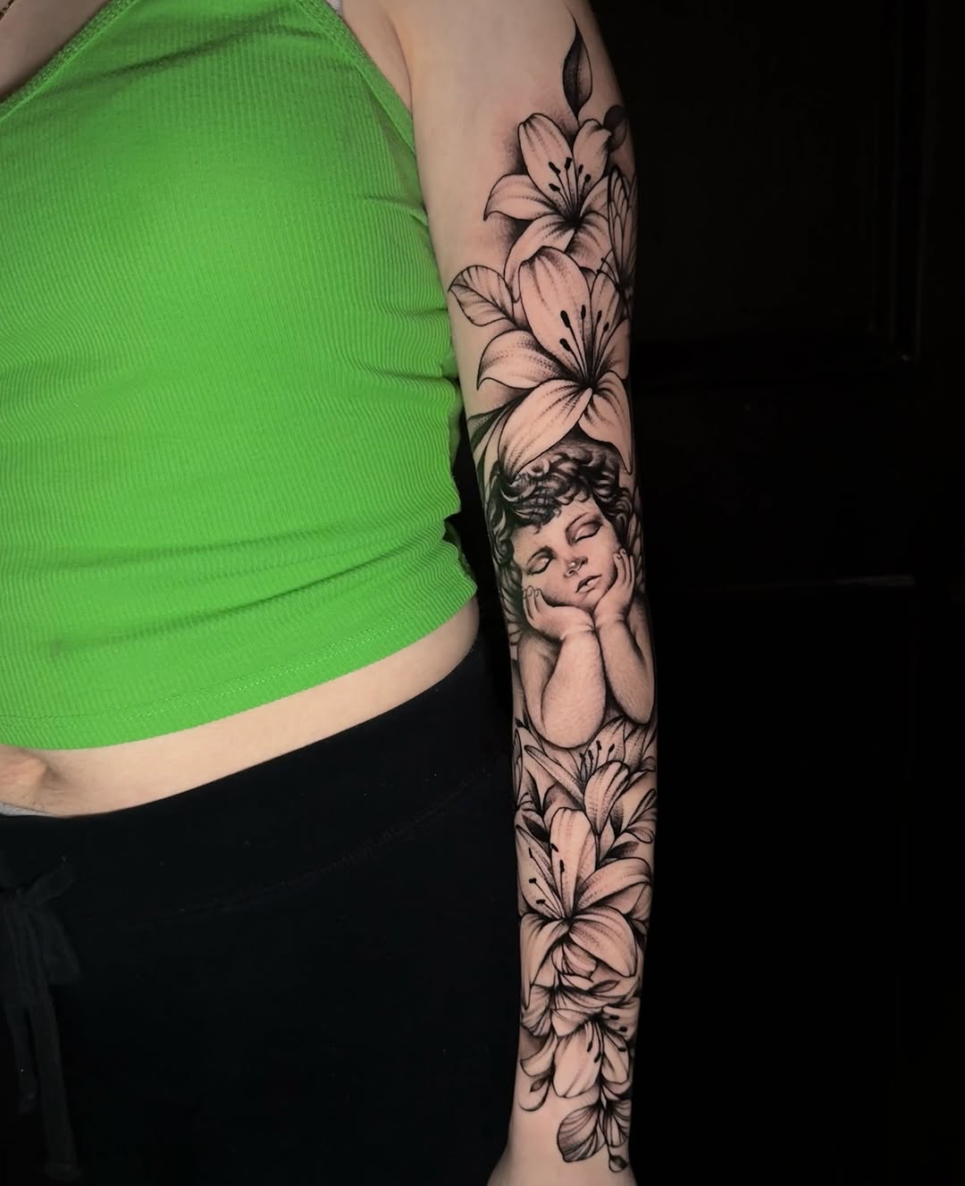 Lilies and cherub black and grey tattoo on the forearm by Tattoo Artist based in Dallas Tx