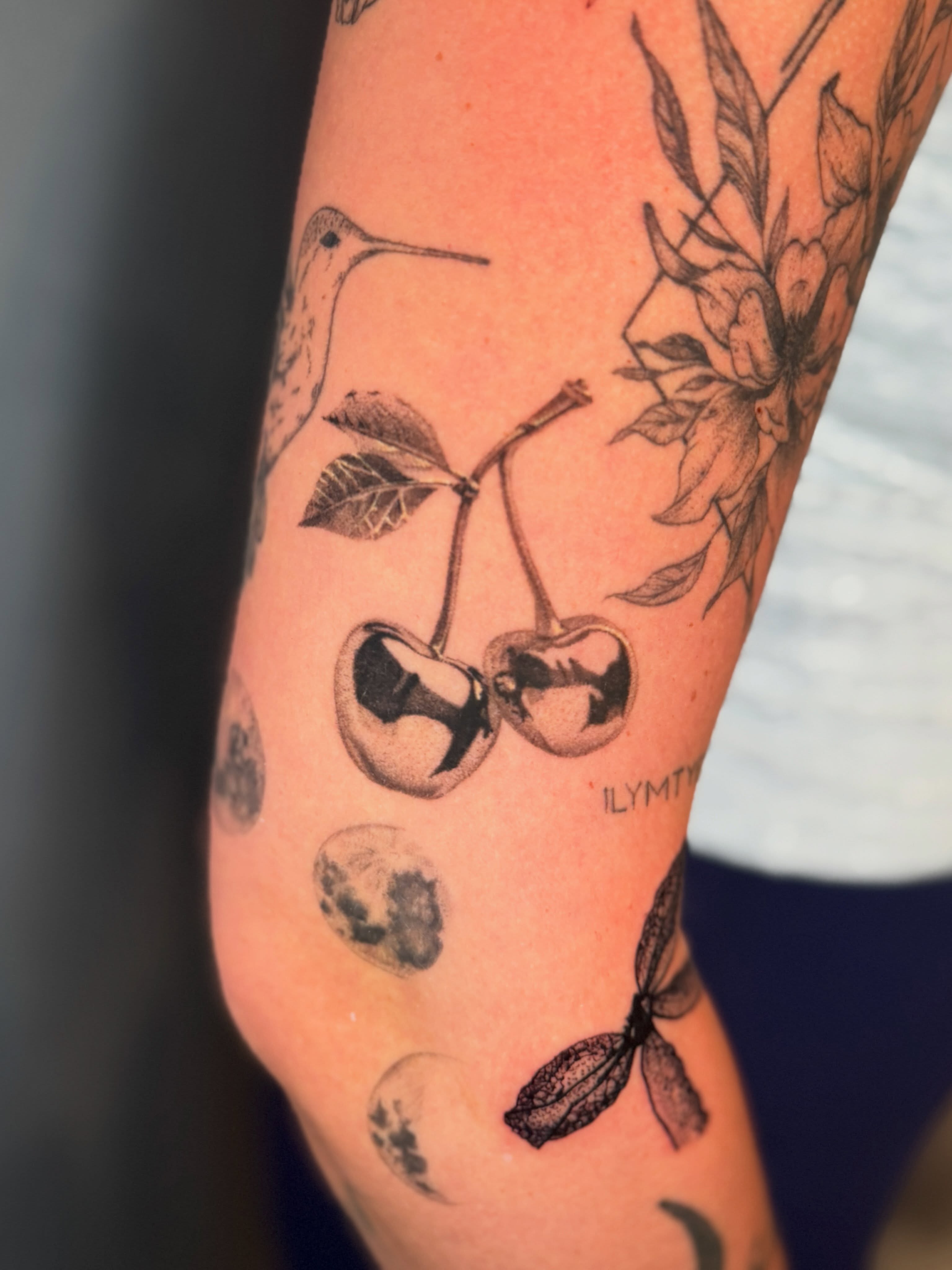 Cherry and hummingbird black and grey tattoo on the forearm by Amber Starr, Midvale, Utah