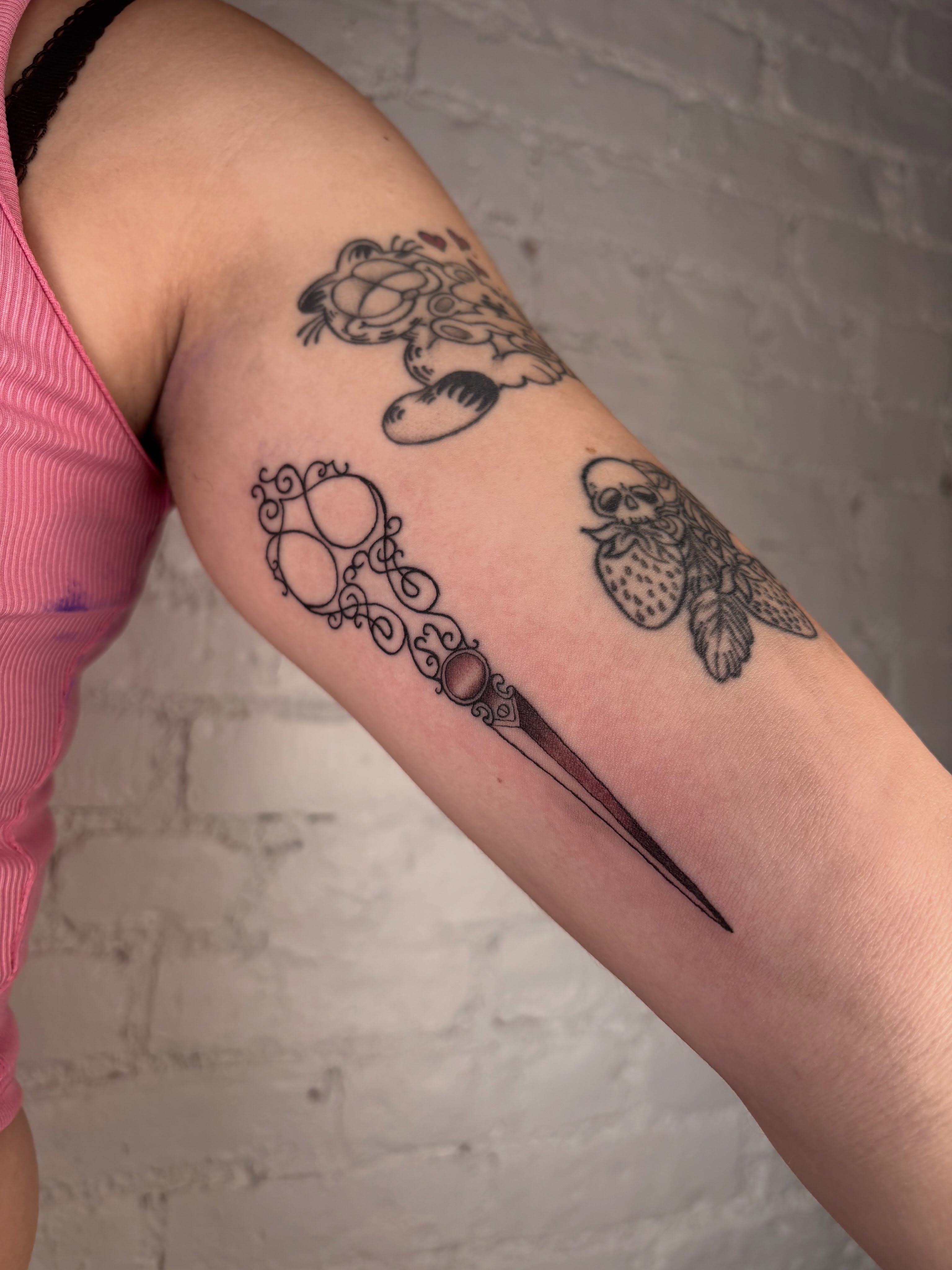 Scissors and skull black and grey tattoo on the forearm by laura bianca
