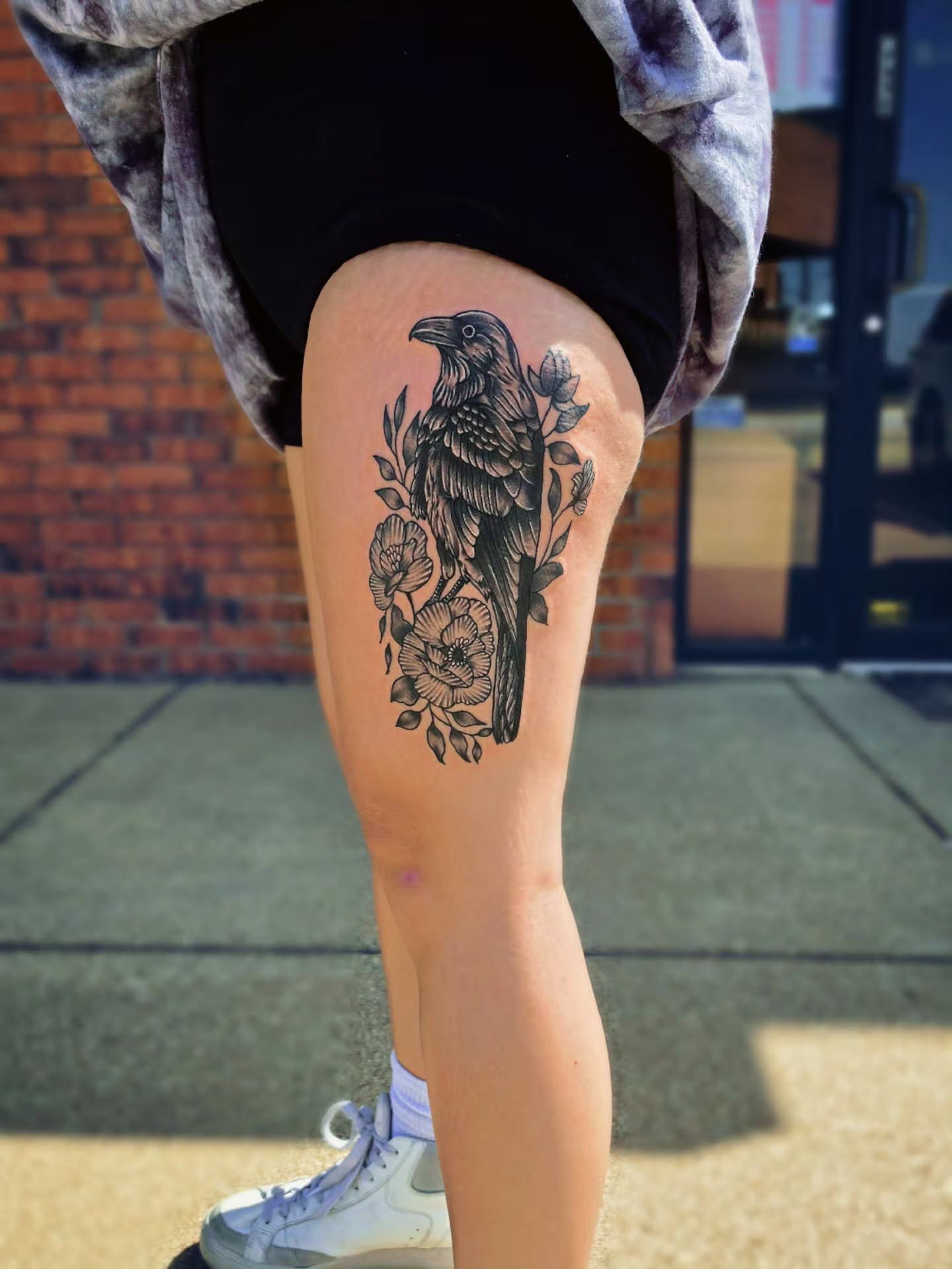 Crow and floral black and grey tattoo on the thigh by DFW