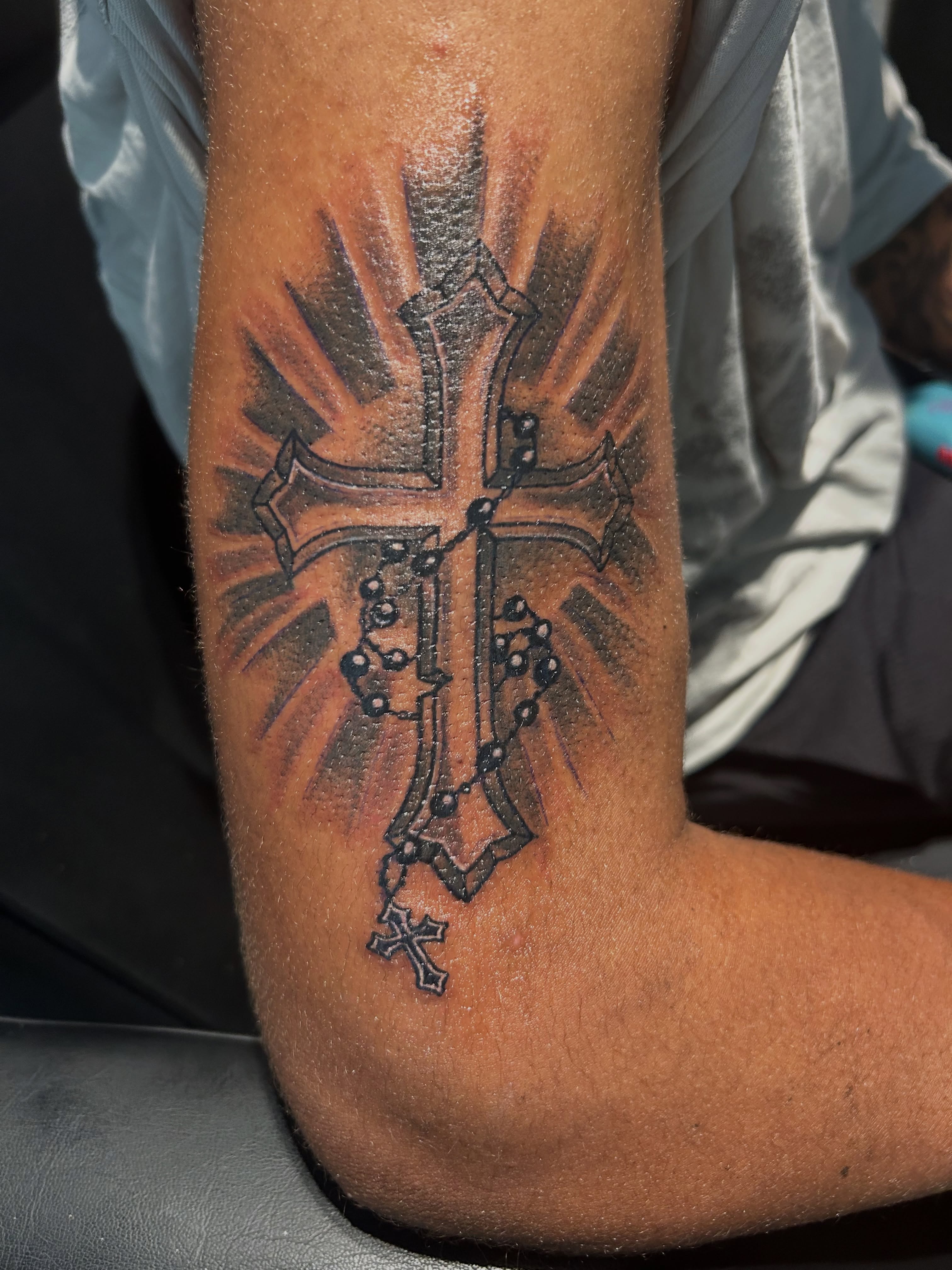 Cross with rosary black and grey tattoo on the forearm by @tatzbythadon