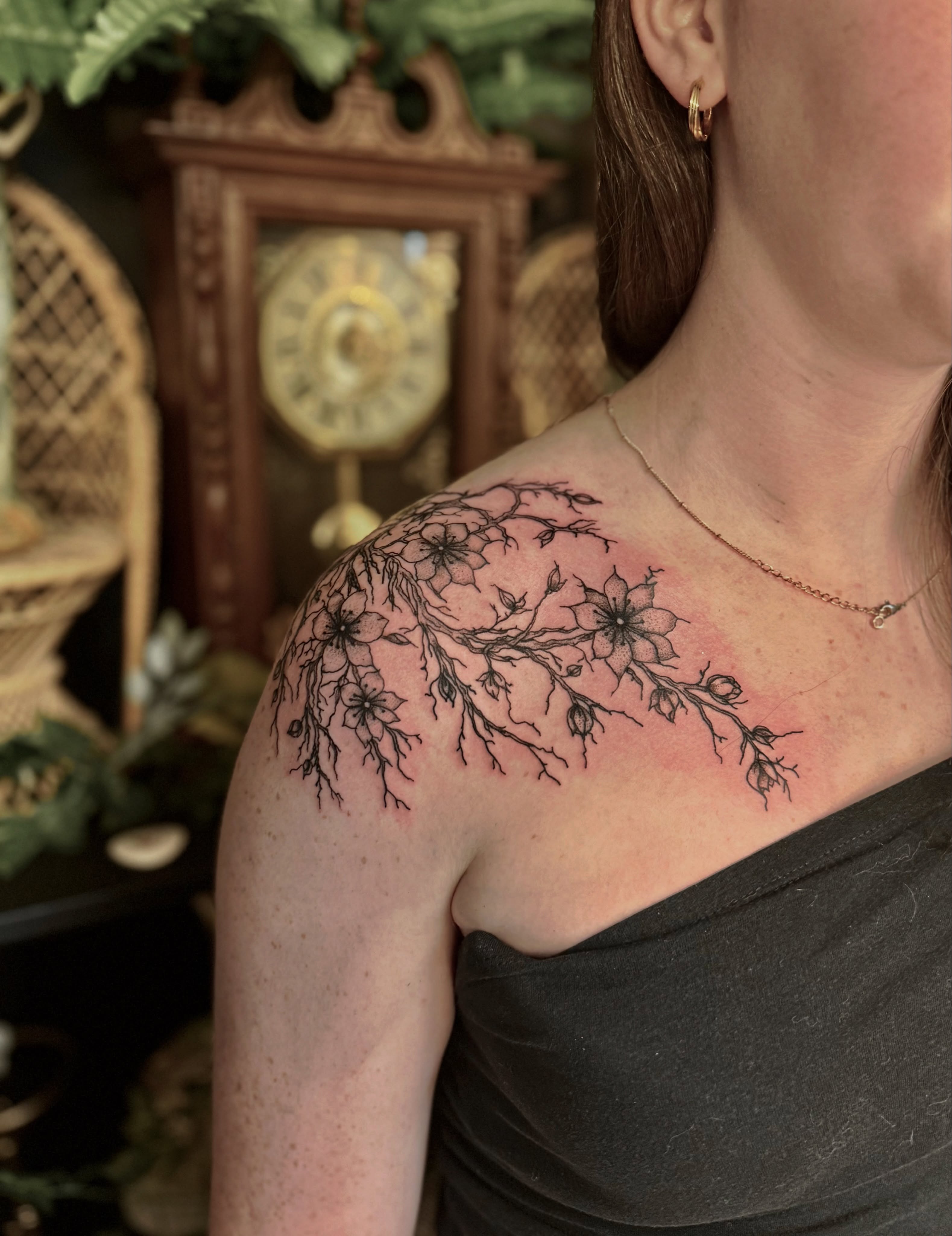 Branch with flowers black and grey tattoo on the shoulder by Haley Bates