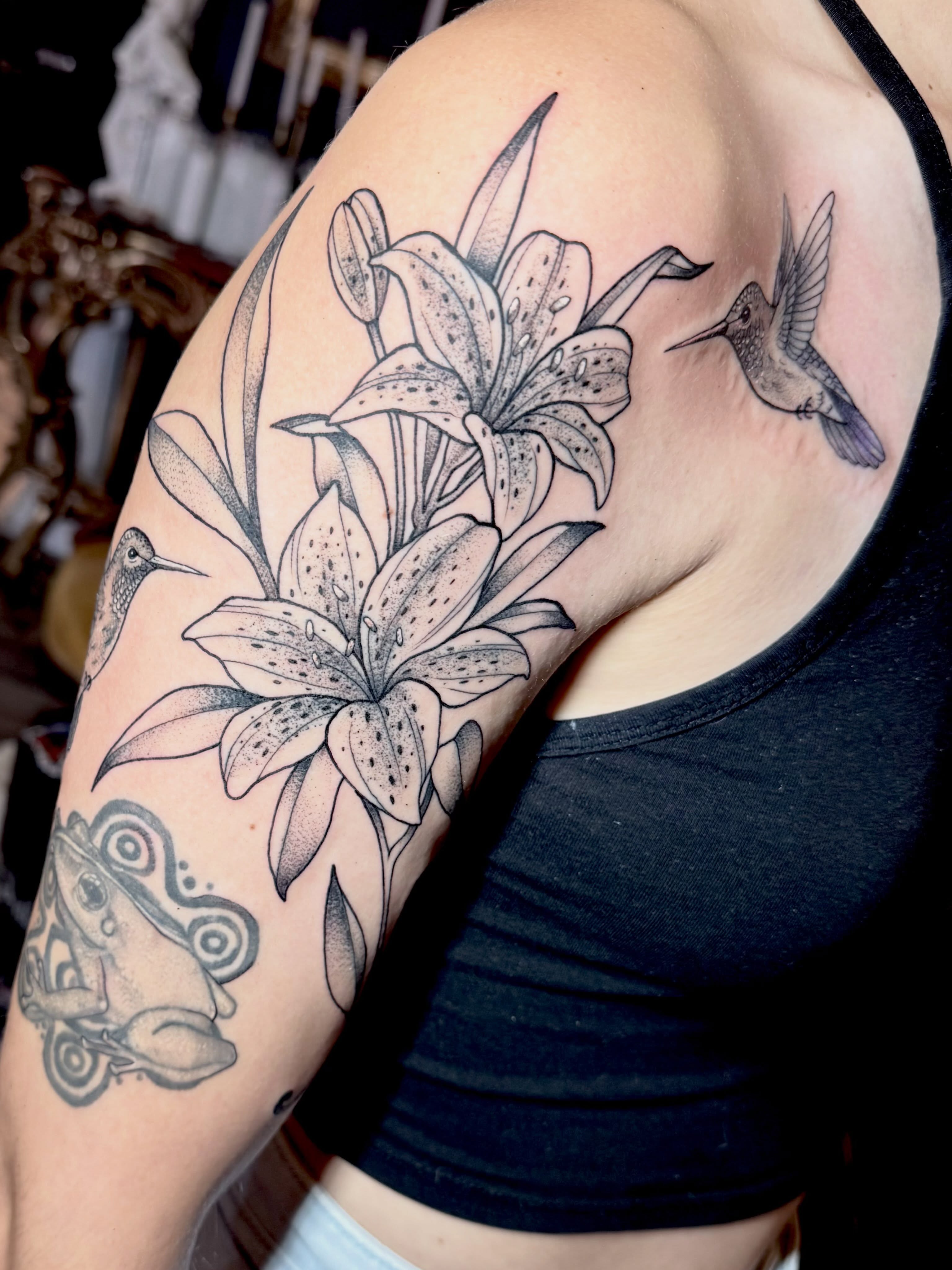 Lilies and hummingbirds dotwork tattoo on the upper arm by Emily Emani, Fremont, Ohio