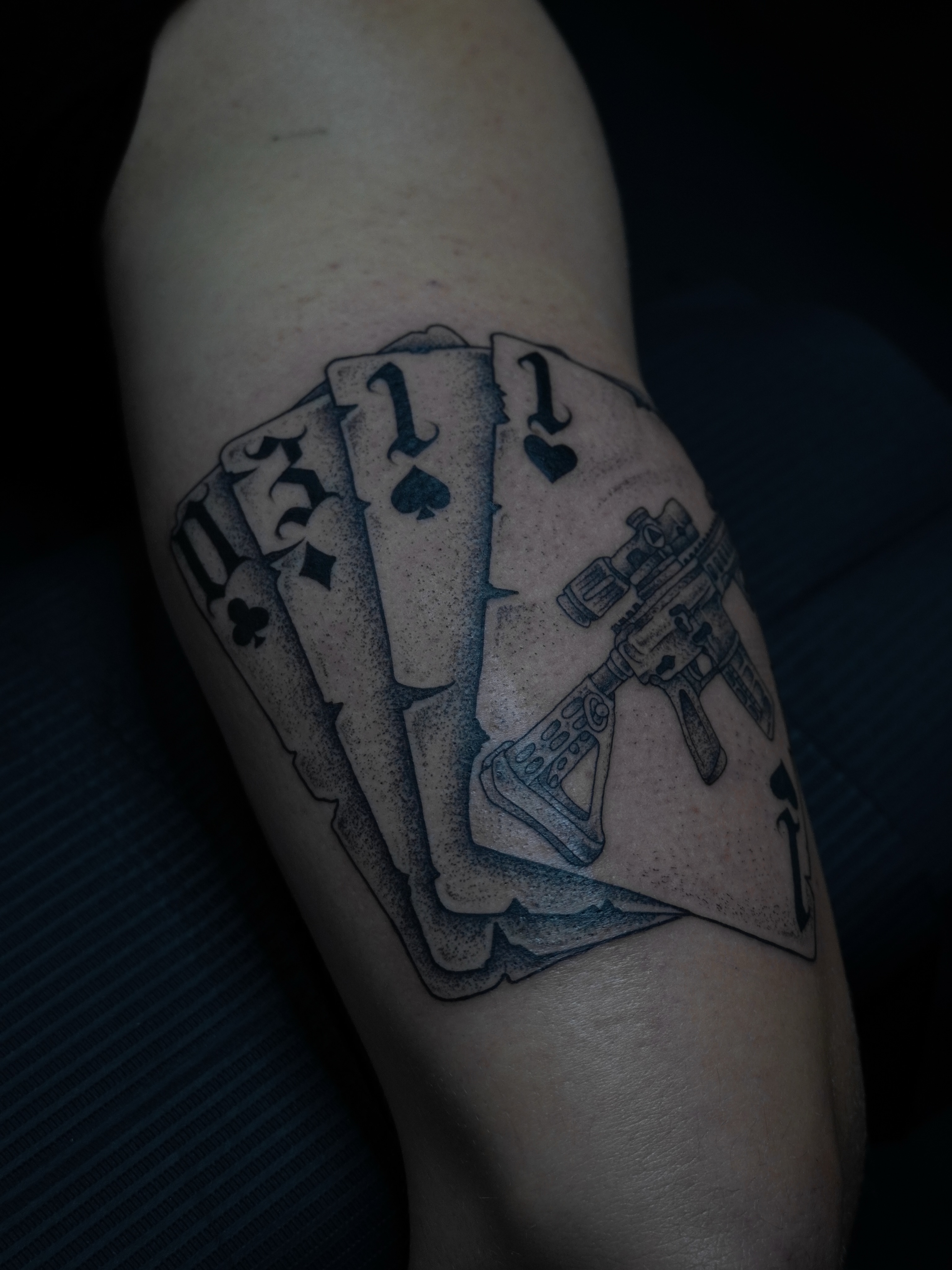Playing cards and gun dotwork tattoo on the forearm by Cory Perry-Servellon