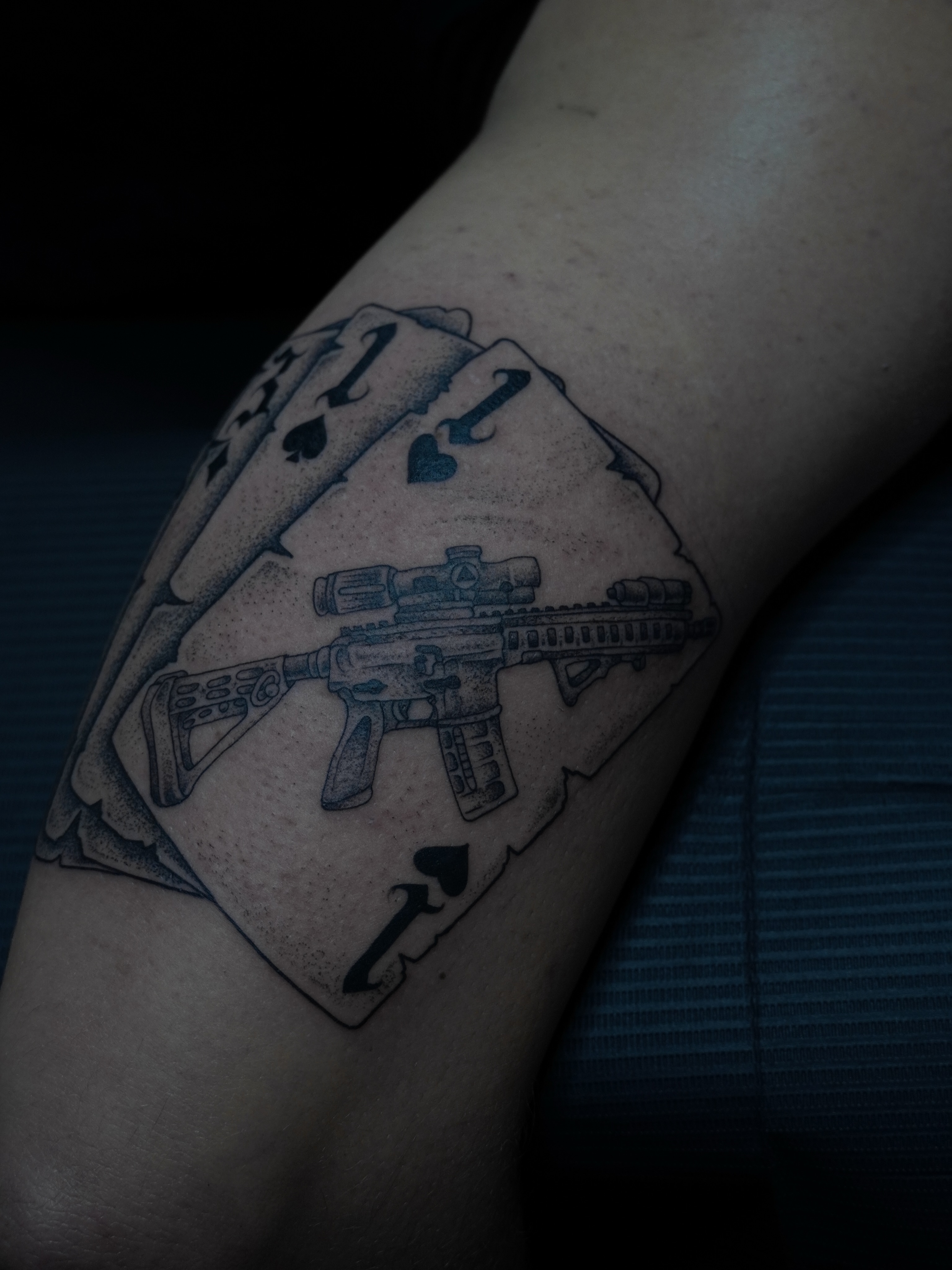Gun and playing cards dotwork tattoo on the forearm by Cory Perry-Servellon