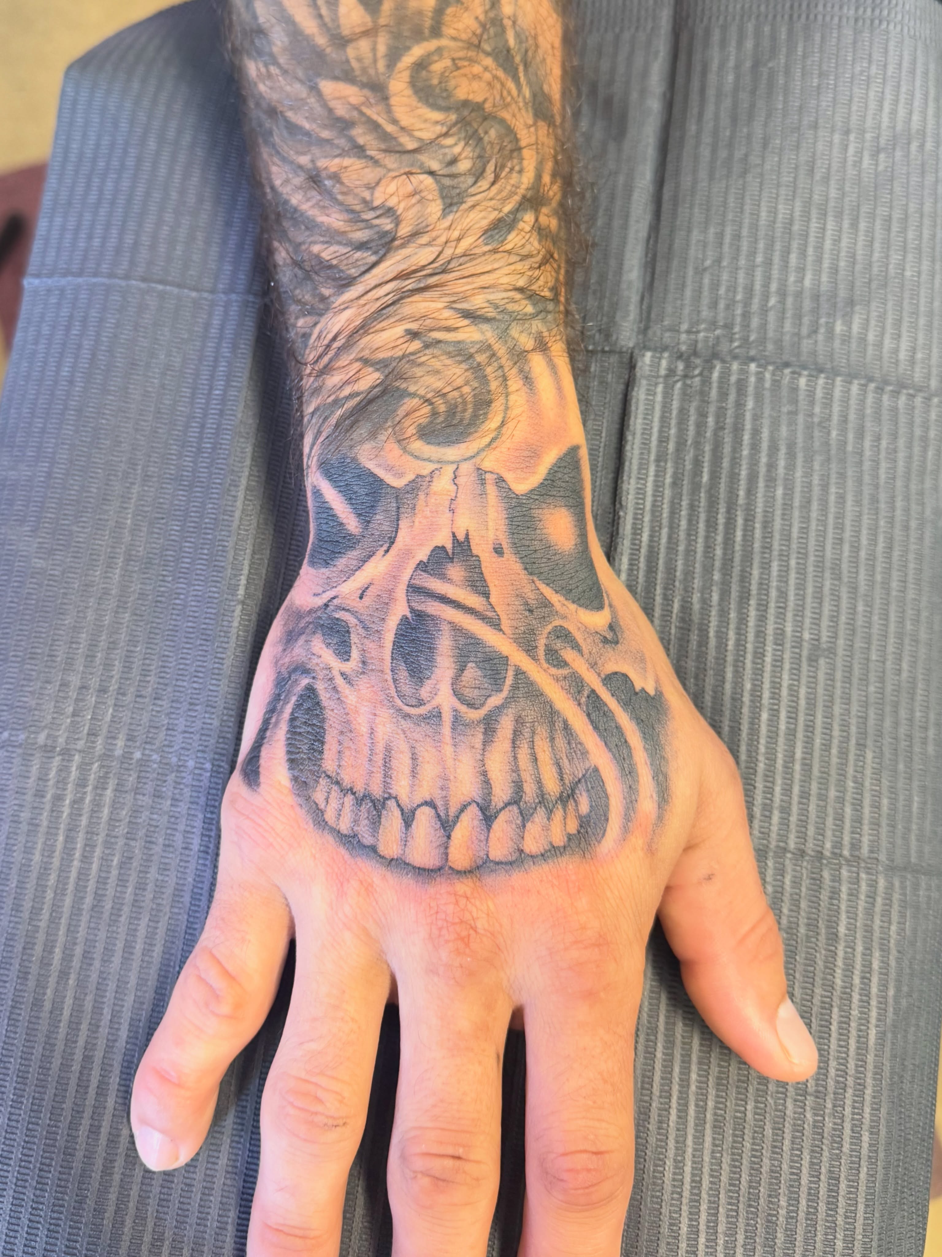 Skull dark realism tattoo on the hand by Cora Phelps