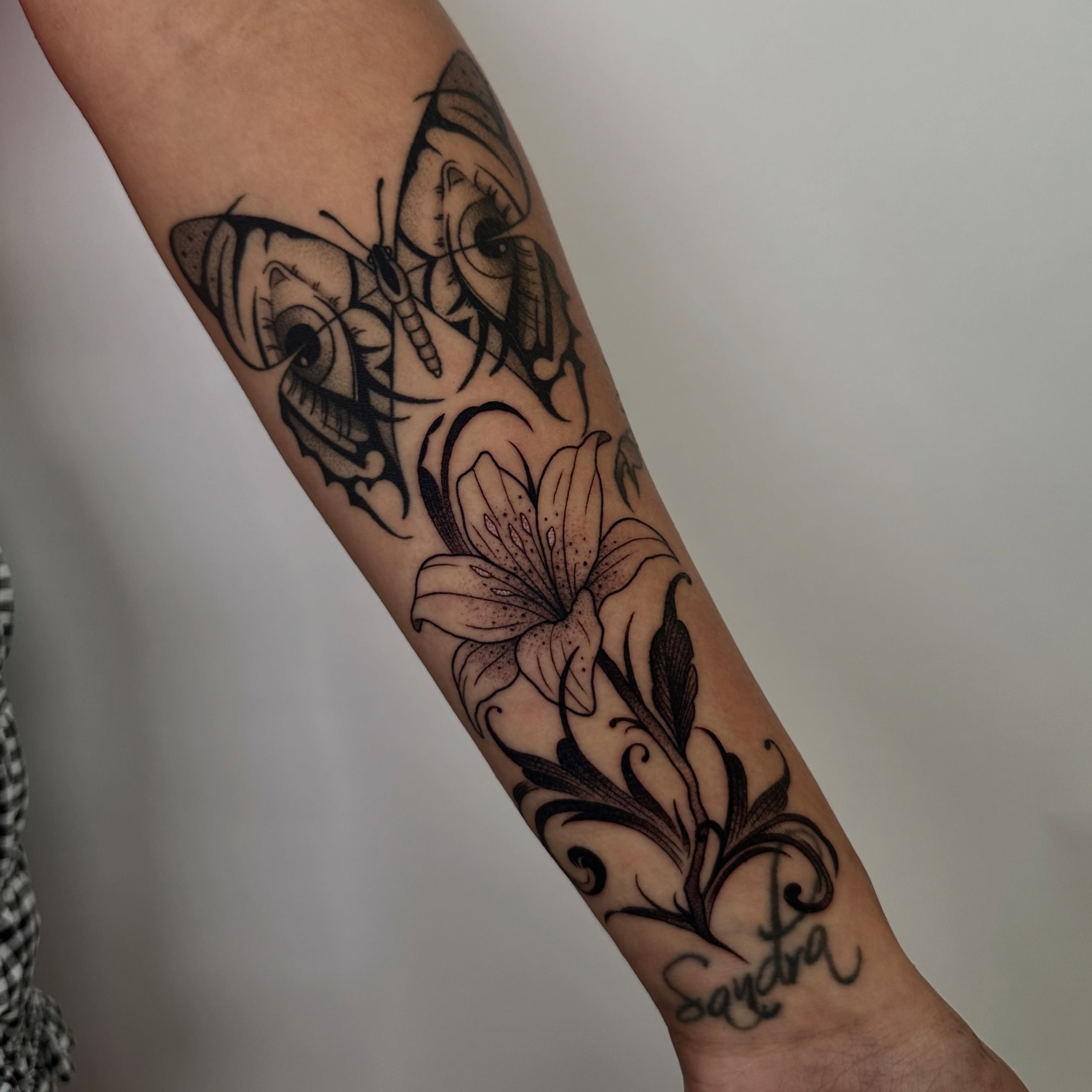 Butterfly and lily realism tattoo on the forearm by Brooklyn Bailey