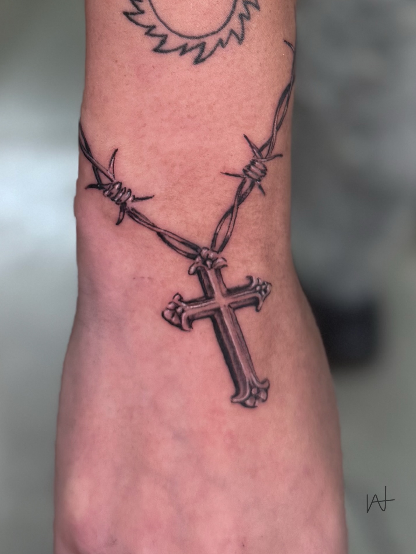 Cross with barbed wire black and grey tattoo on the forearm by Kat Parmu