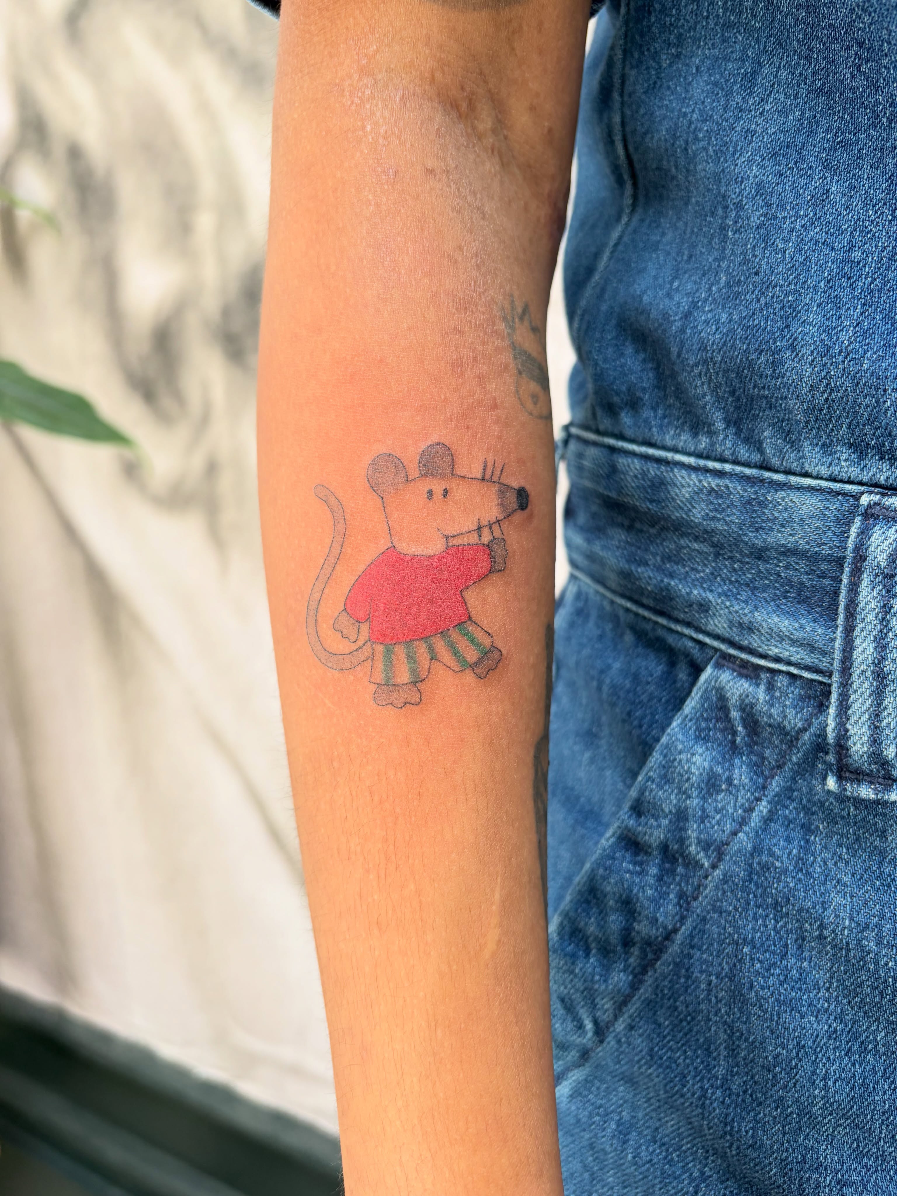 Mouse wearing clothes illustrative tattoo on the forearm by Kyra Monterrosa