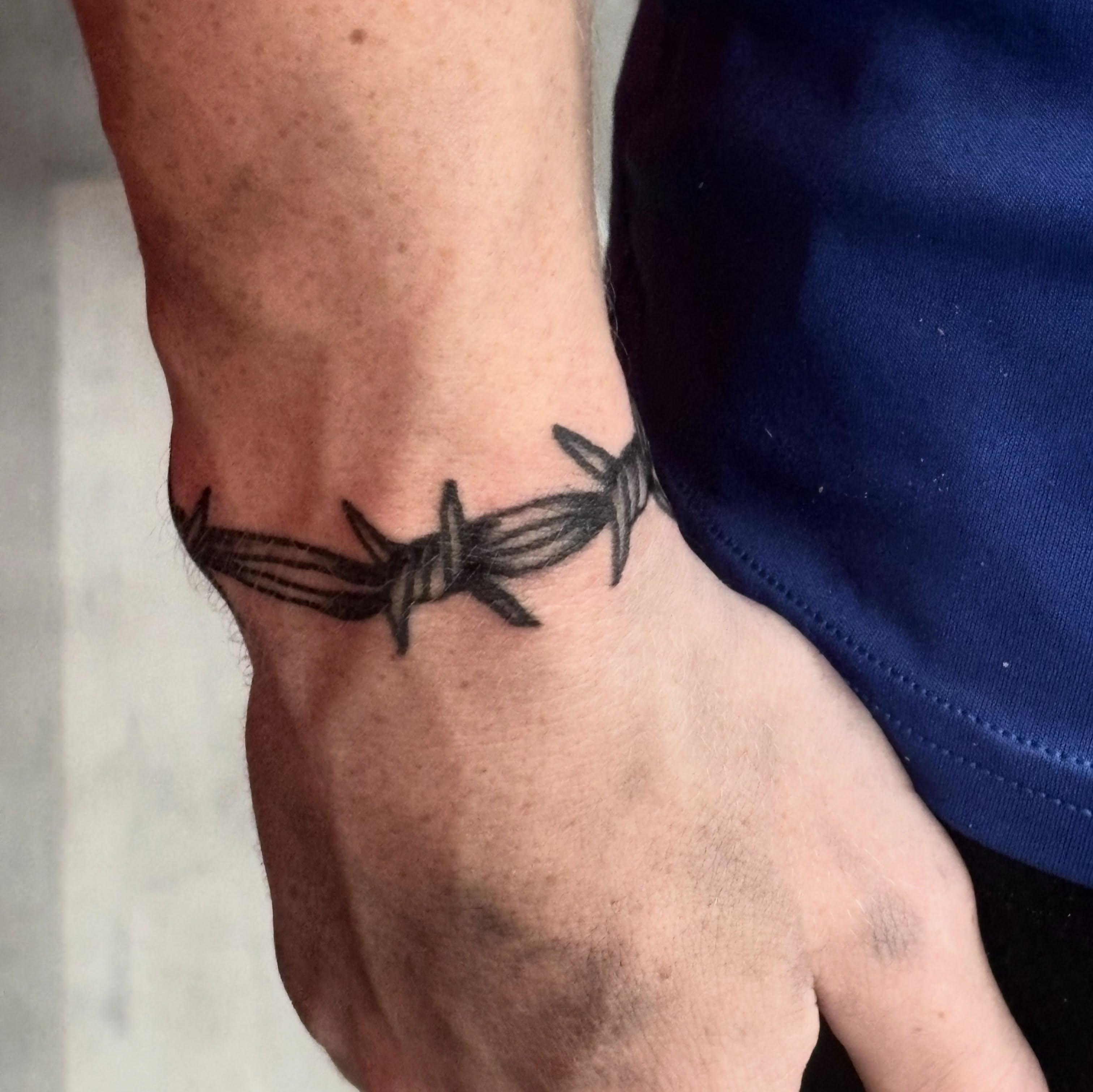 Barbed wire black and grey tattoo on the forearm by Landon Bagley