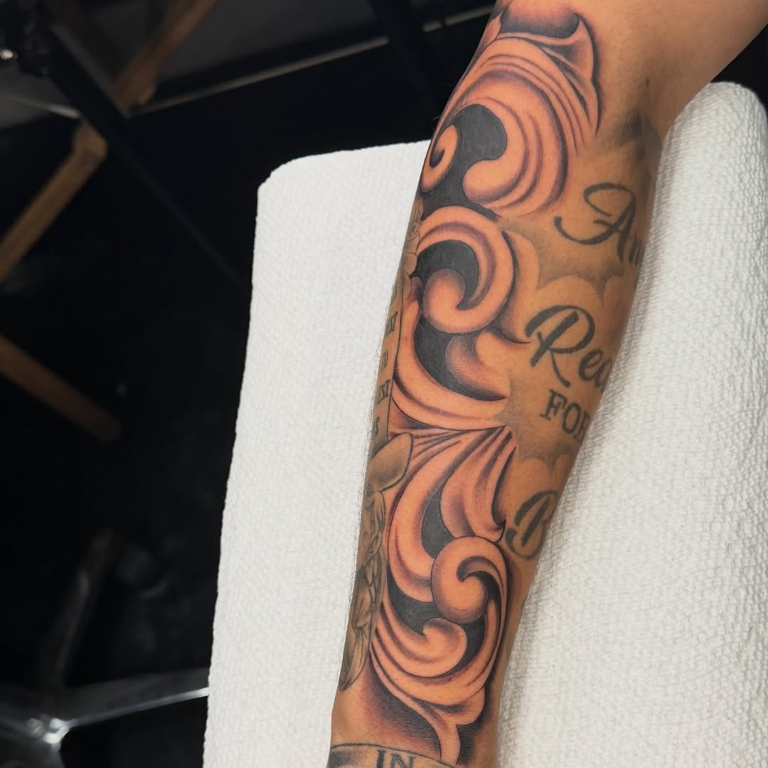Swirls and lettering black and grey tattoo on the forearm by Kimberly landin