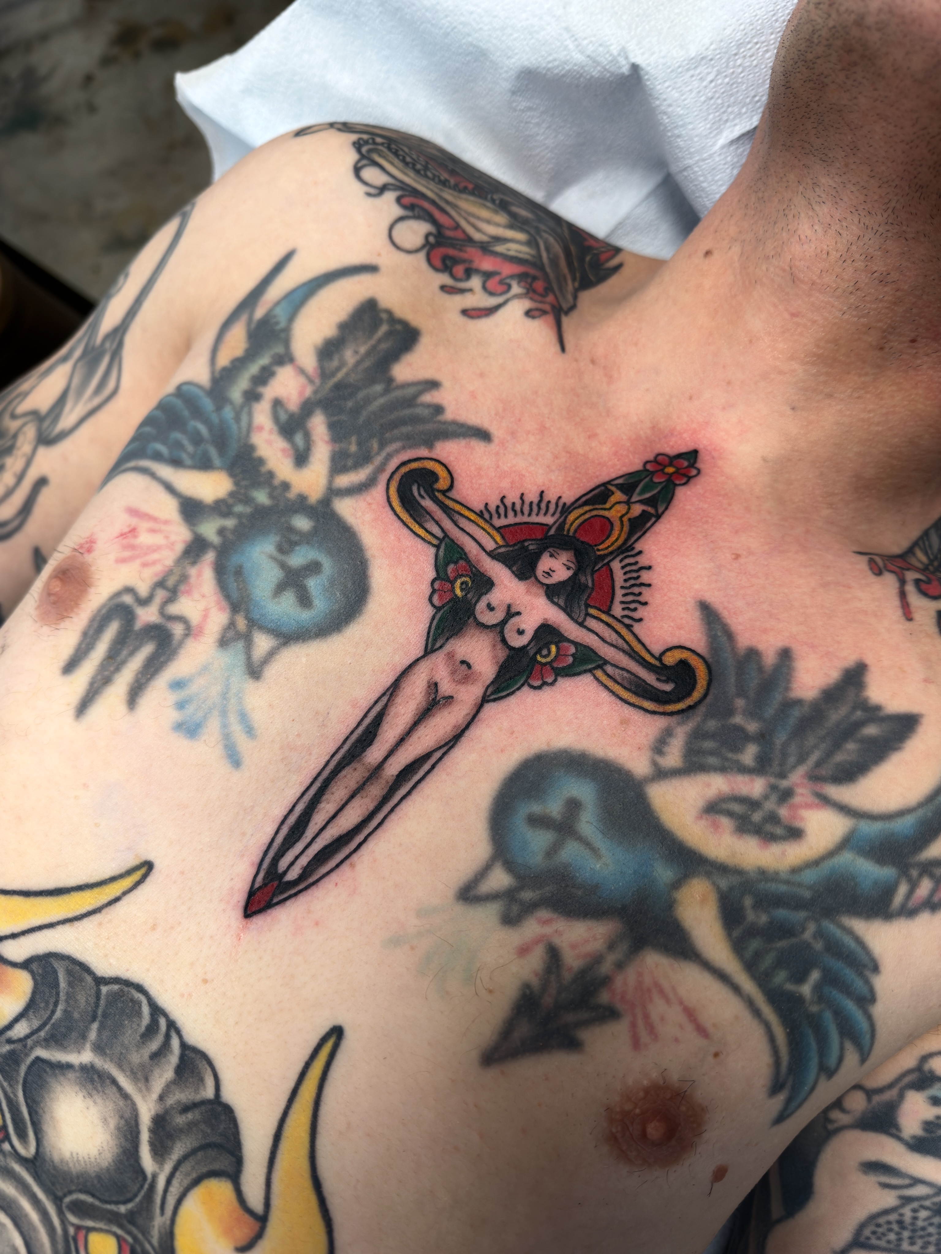 Naked woman with sword American traditional tattoo on the chest by Christopher Layman