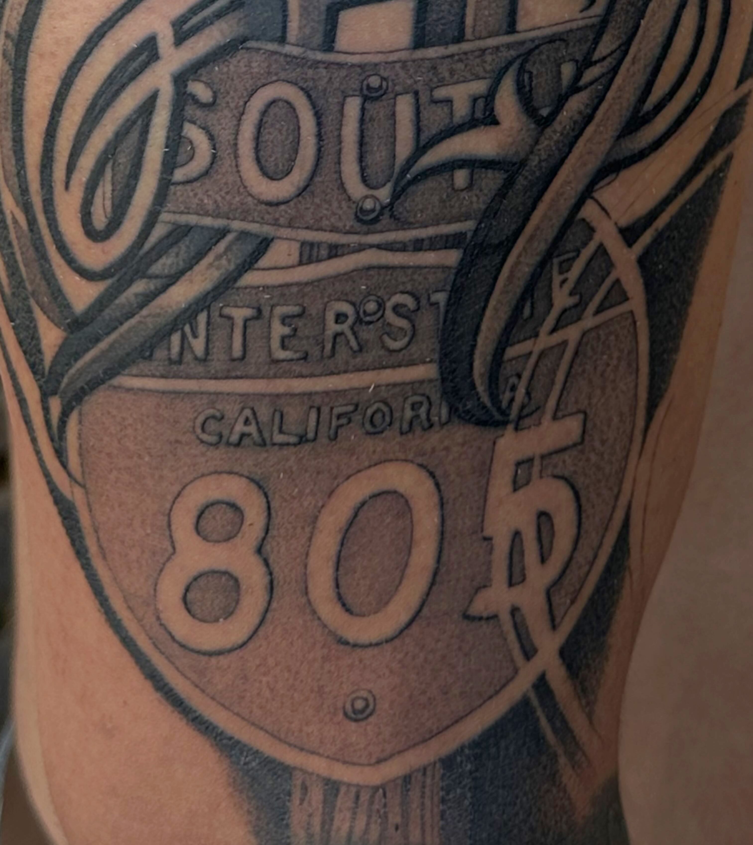 Interstate highway sign black and grey tattoo on the forearm by San Diego Tattoo Artist