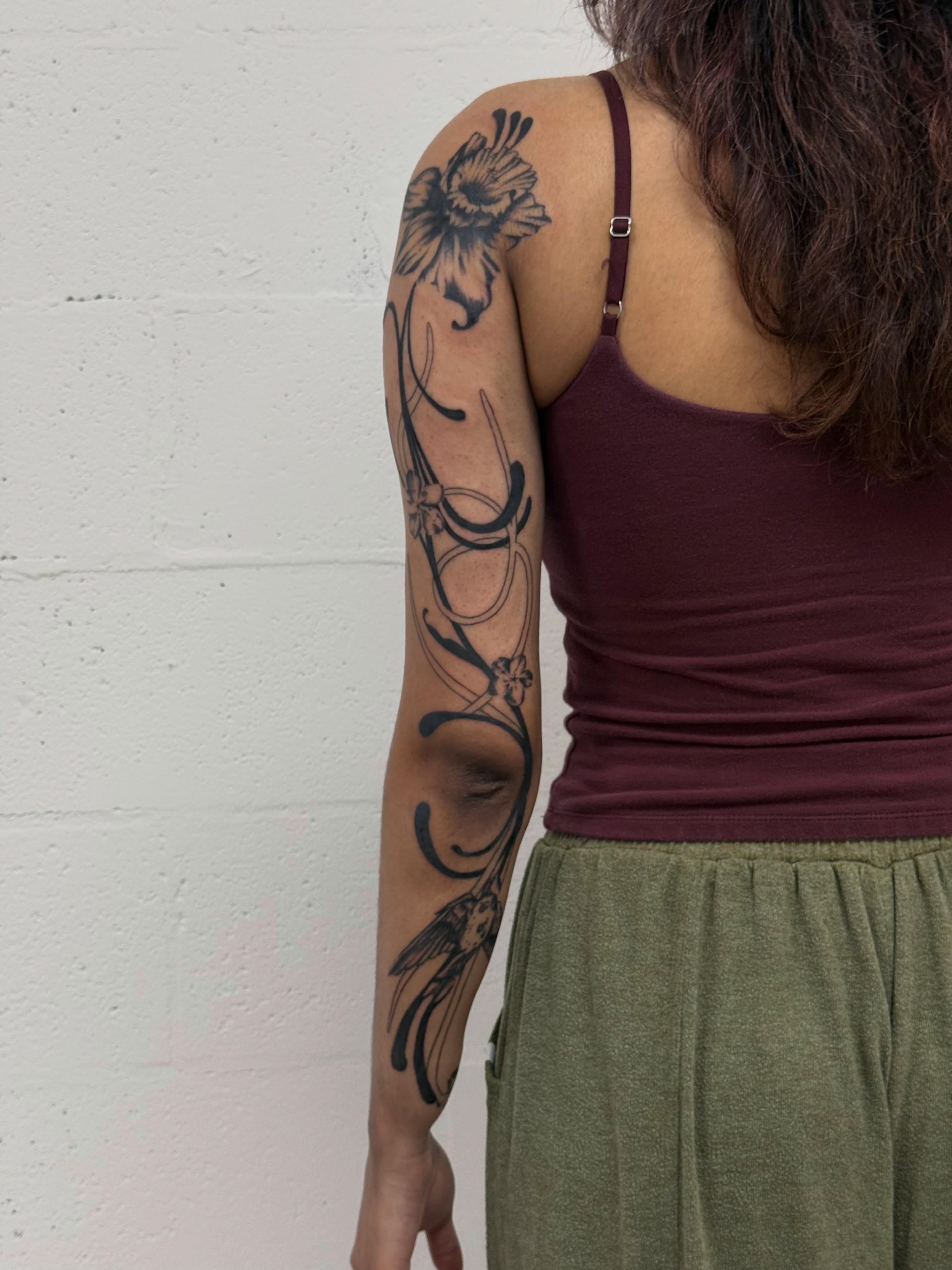 Floral design black and grey tattoo on the upper arm by Ava Nilou