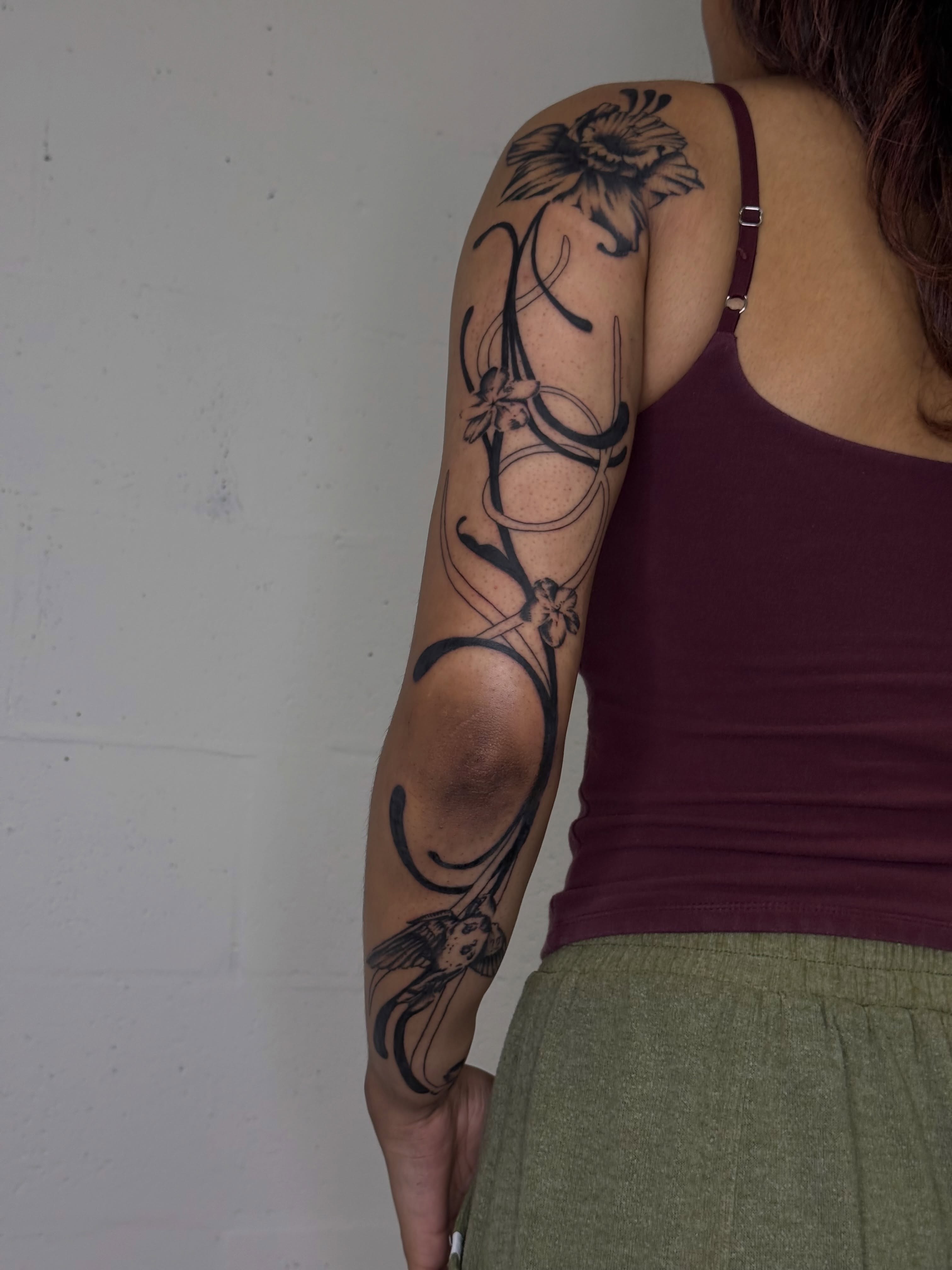 Floral design black and grey tattoo on the upper arm by Ava Nilou