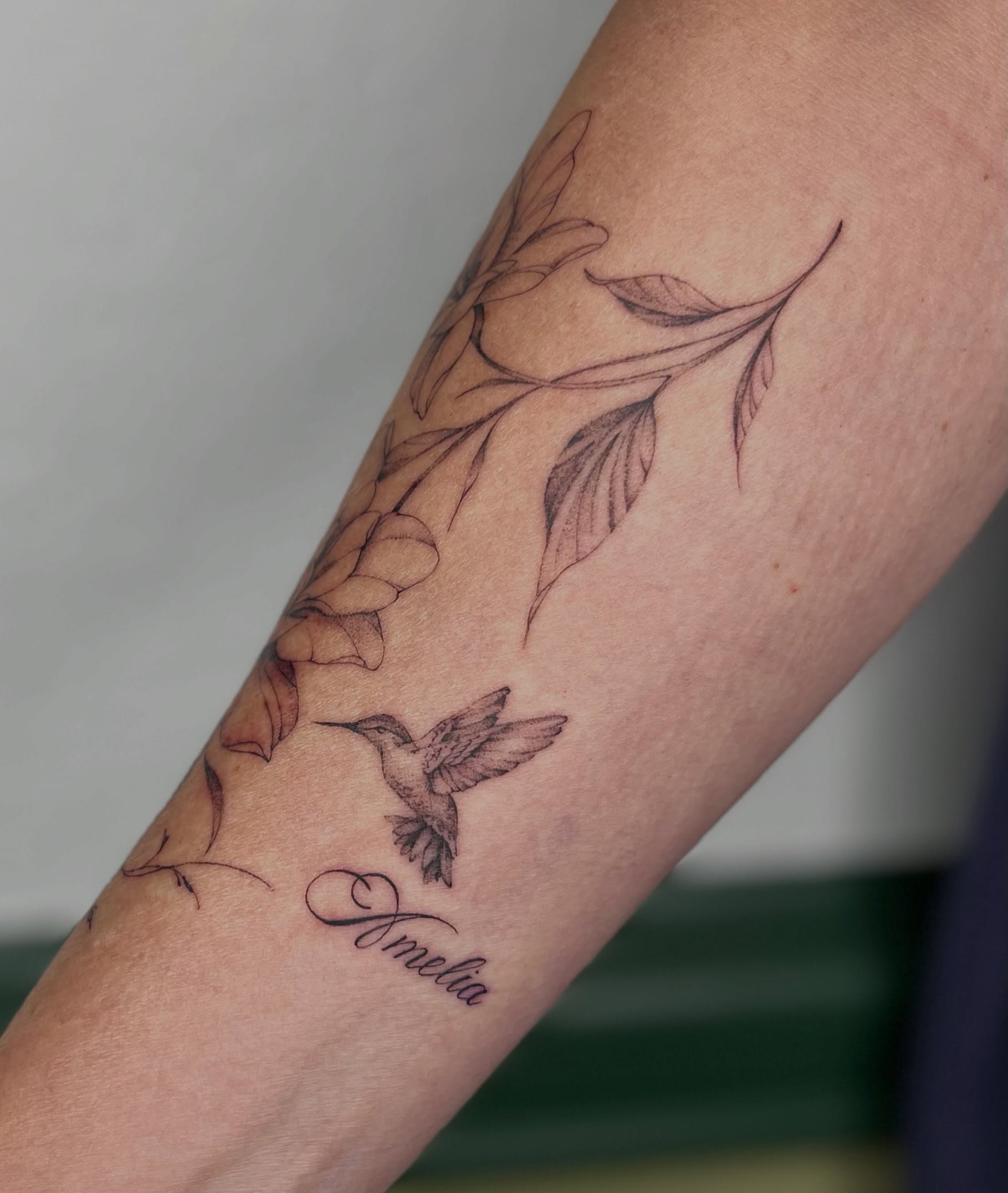 Hummingbird and flowers realism tattoo on the forearm by Ash F