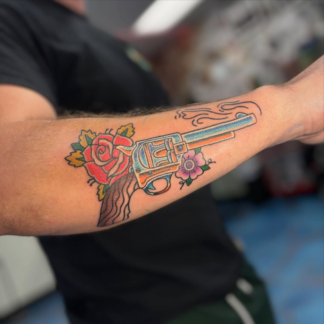 Revolver and flowers American traditional tattoo on the forearm by Cam Sykes