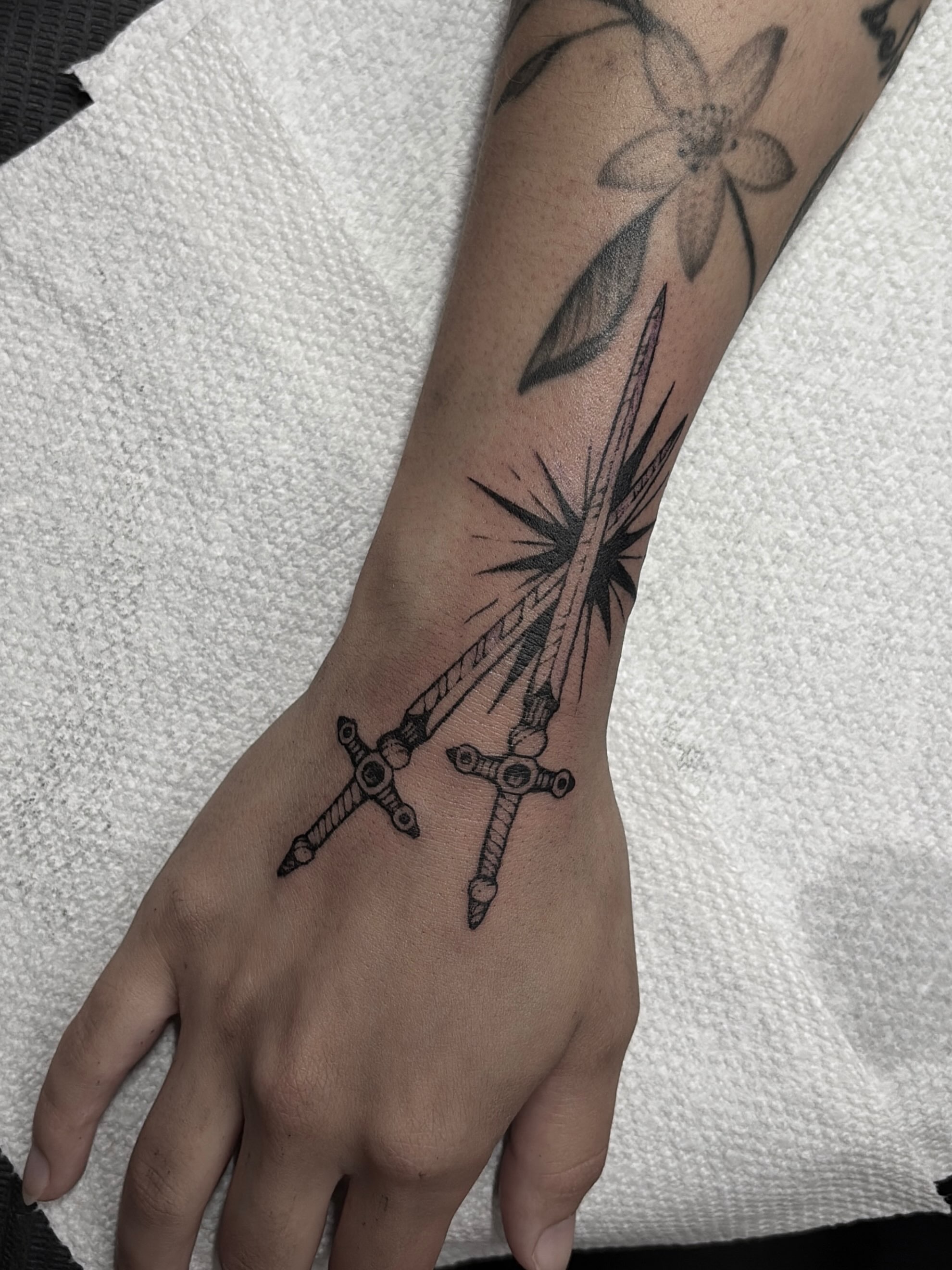 Crosses and starburst black and grey tattoo on the forearm by Harlee Hornsby