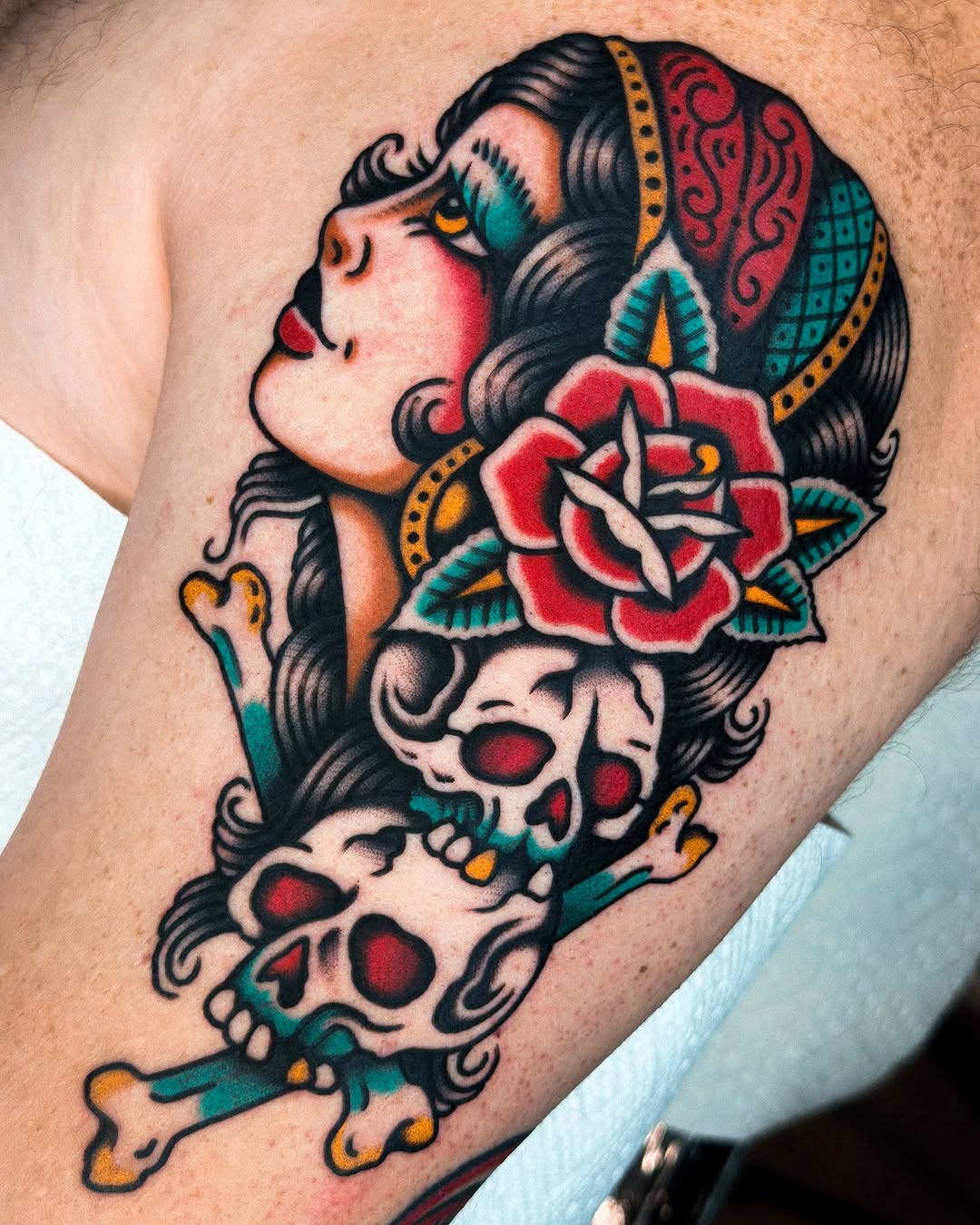 Woman with skull American traditional tattoo on the upper arm by Samuel Dickey