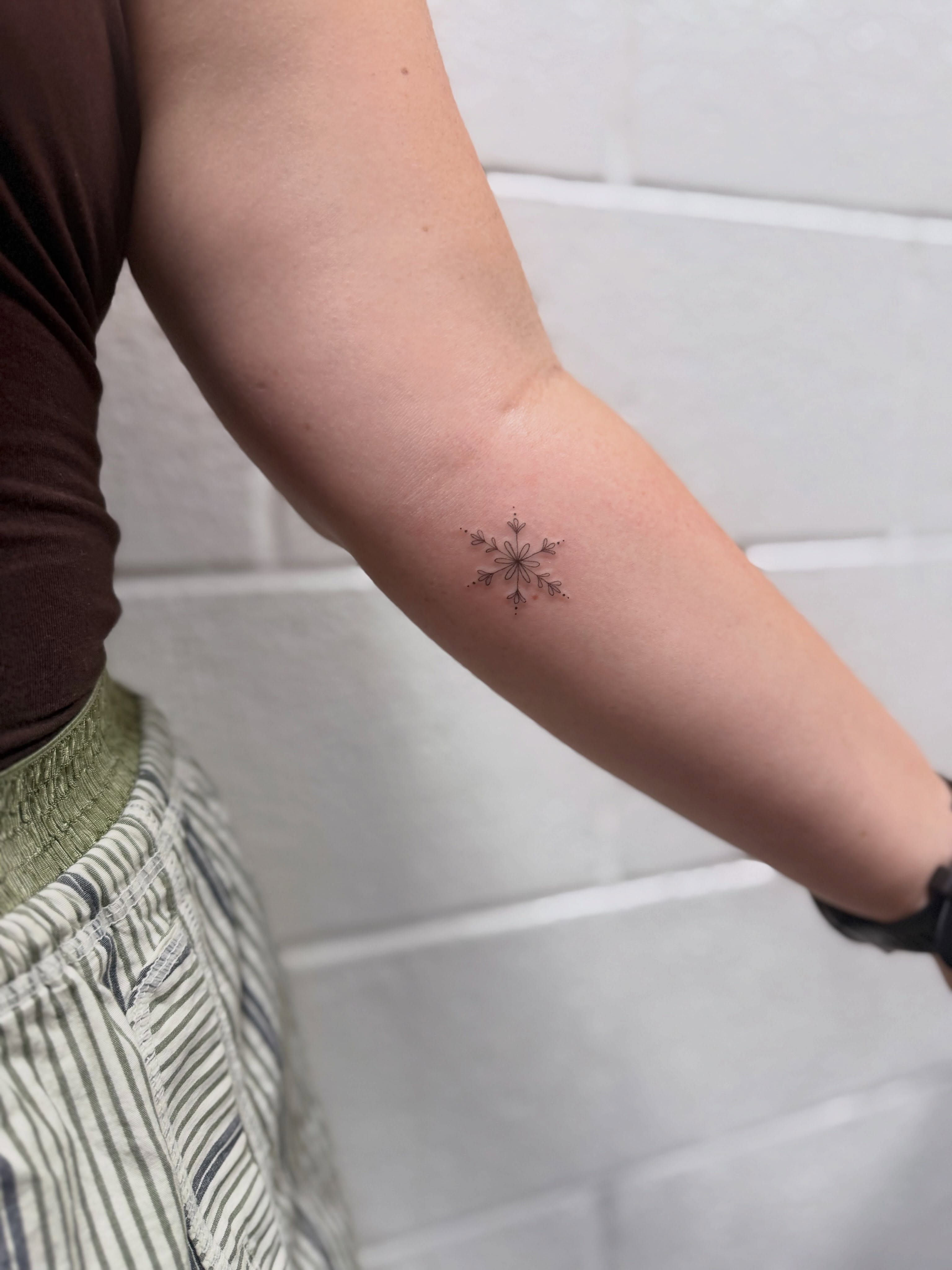 Snowflake geometric tattoo on the forearm by Reverie Studio