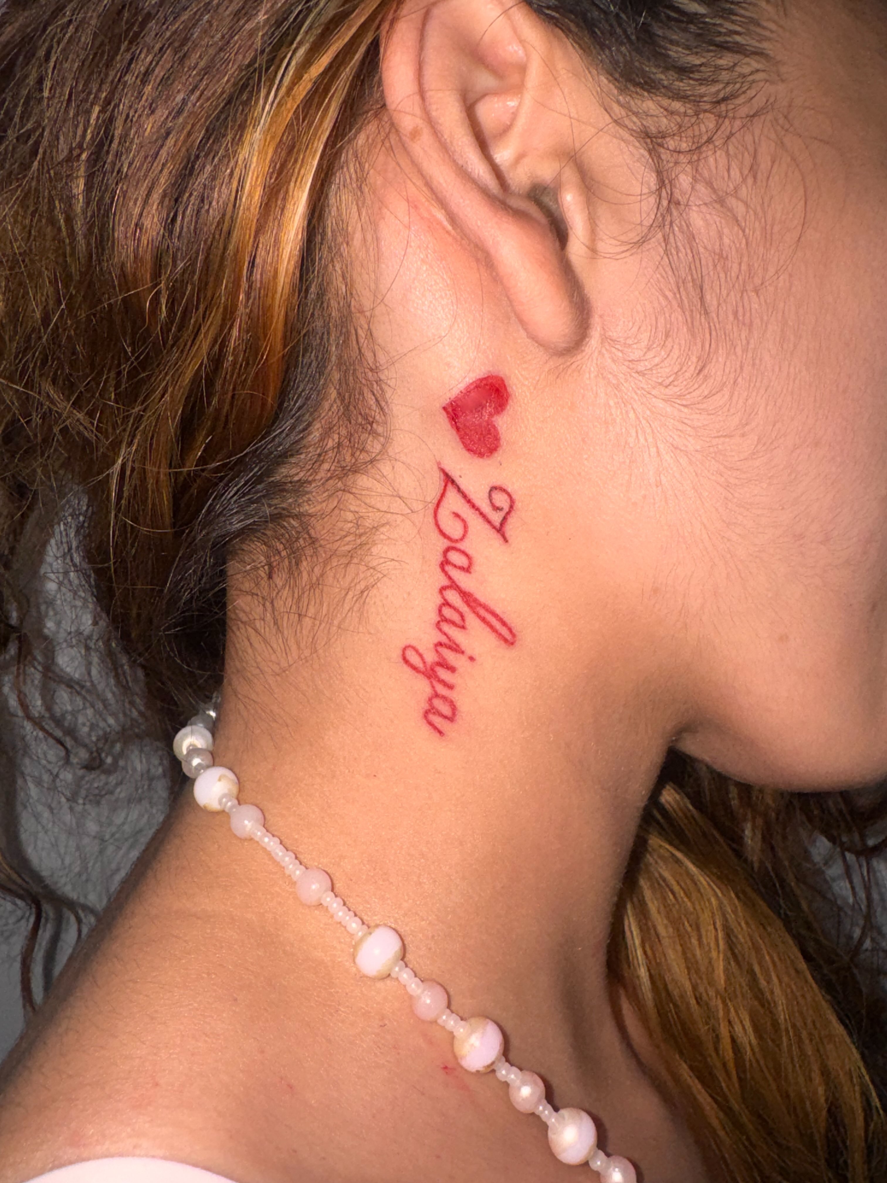 Name with heart lettering script tattoo on the neck by Comet