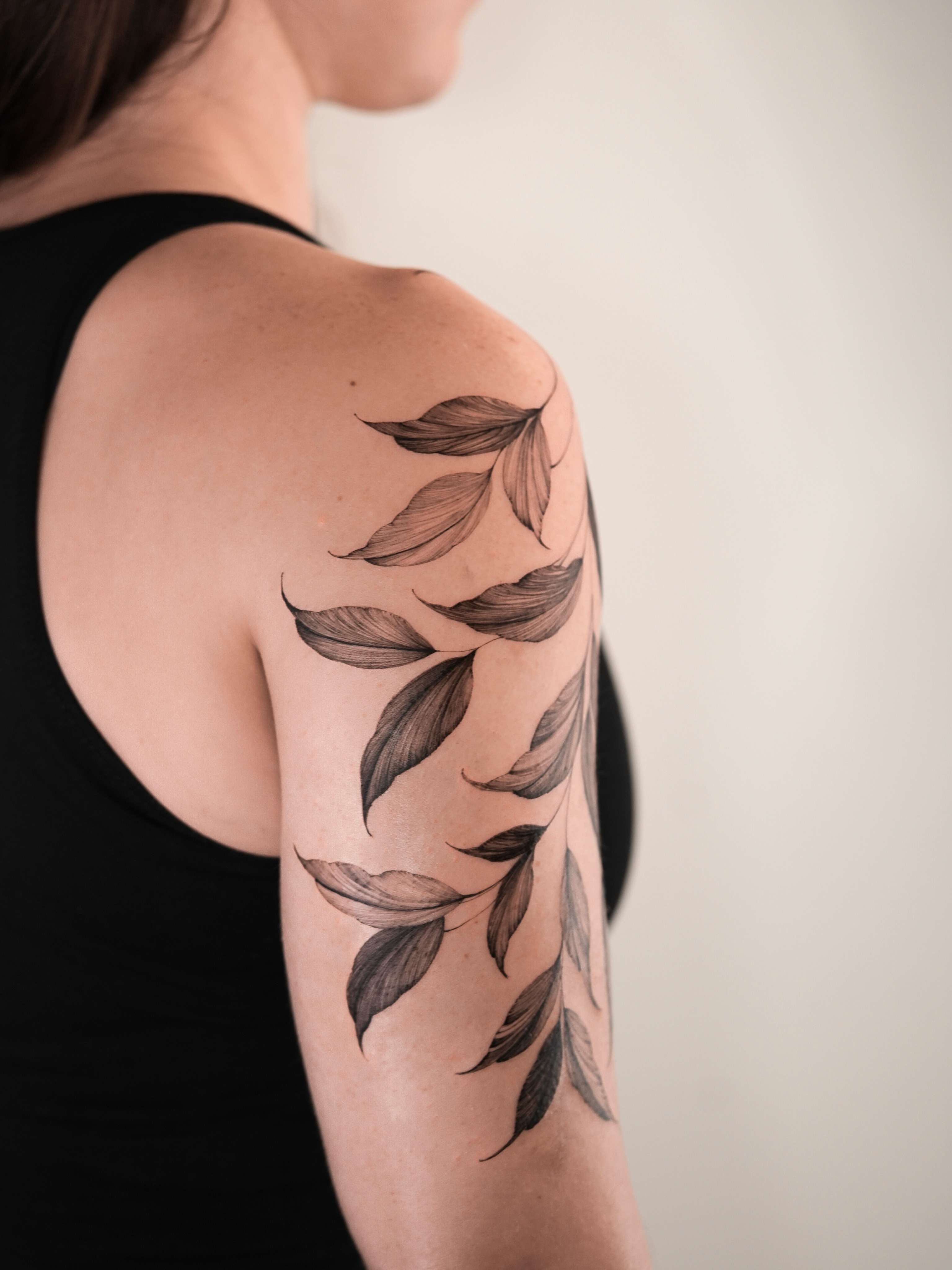 Leaf black and grey tattoo on the upper arm by Zalina Loriia