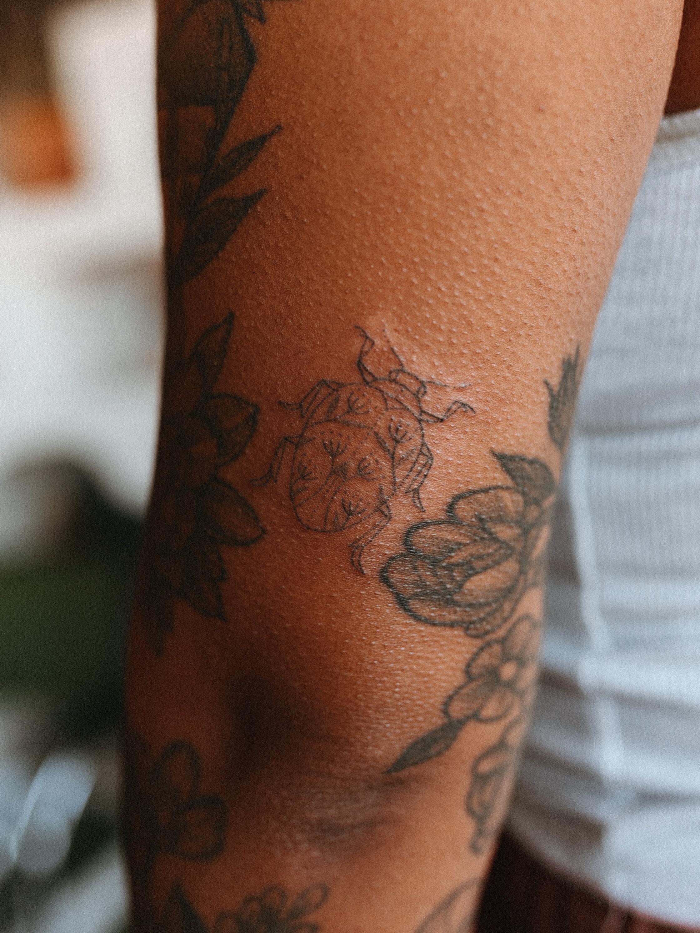 Flower and bug black and grey tattoo on the forearm by Grace Wise - Handpoke Tattoos