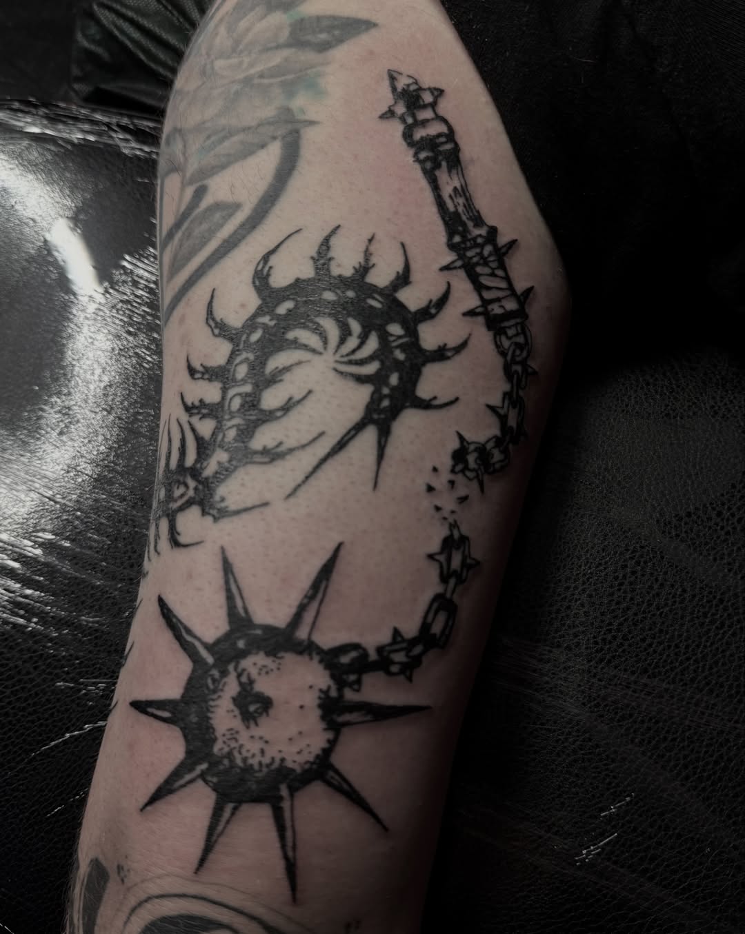 Spiked spheres and chain black and grey tattoo on the forearm by Jordan Sandoval