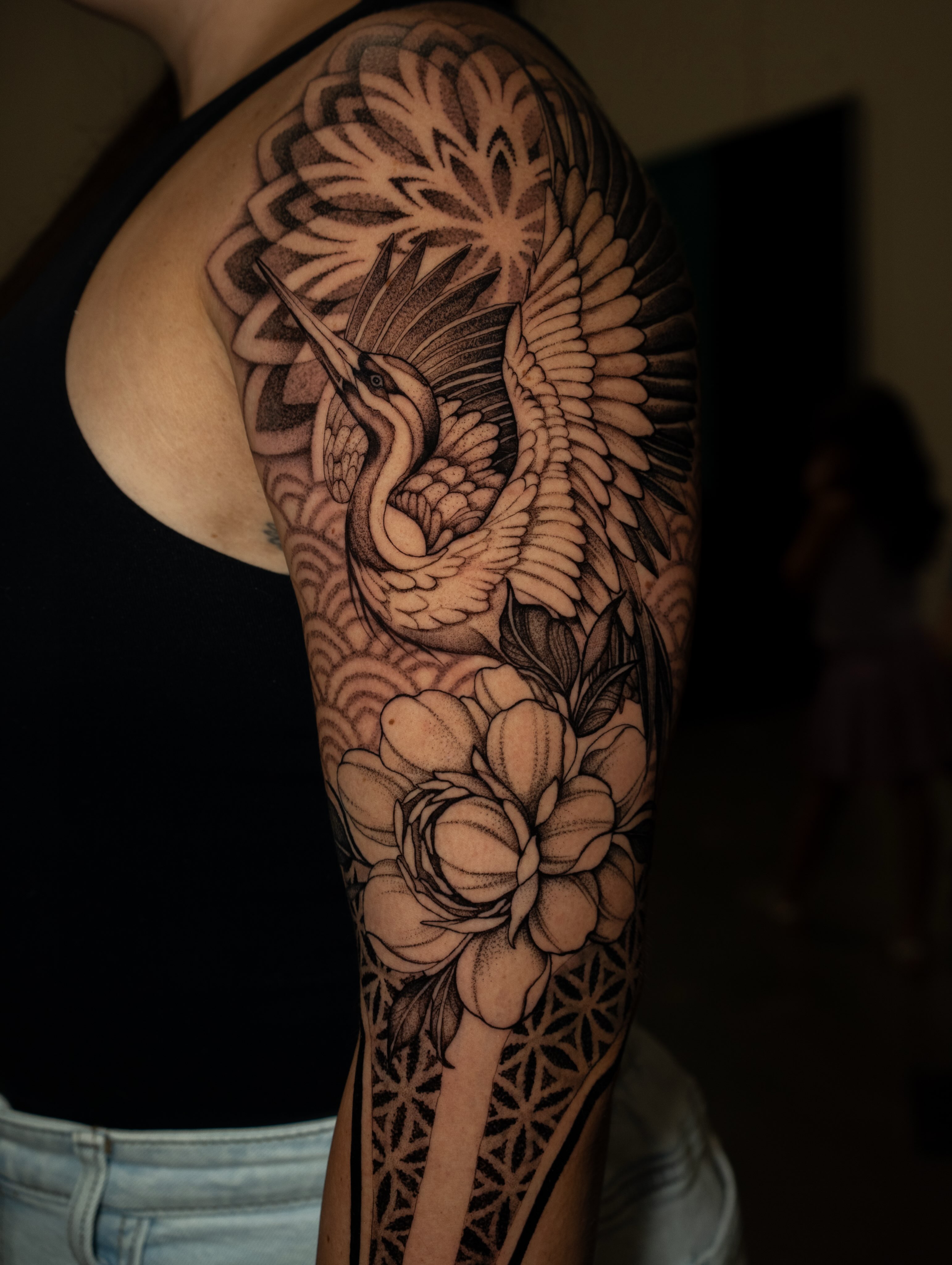 Heron and lotus realism tattoo on the upper arm by Katherin Plaza