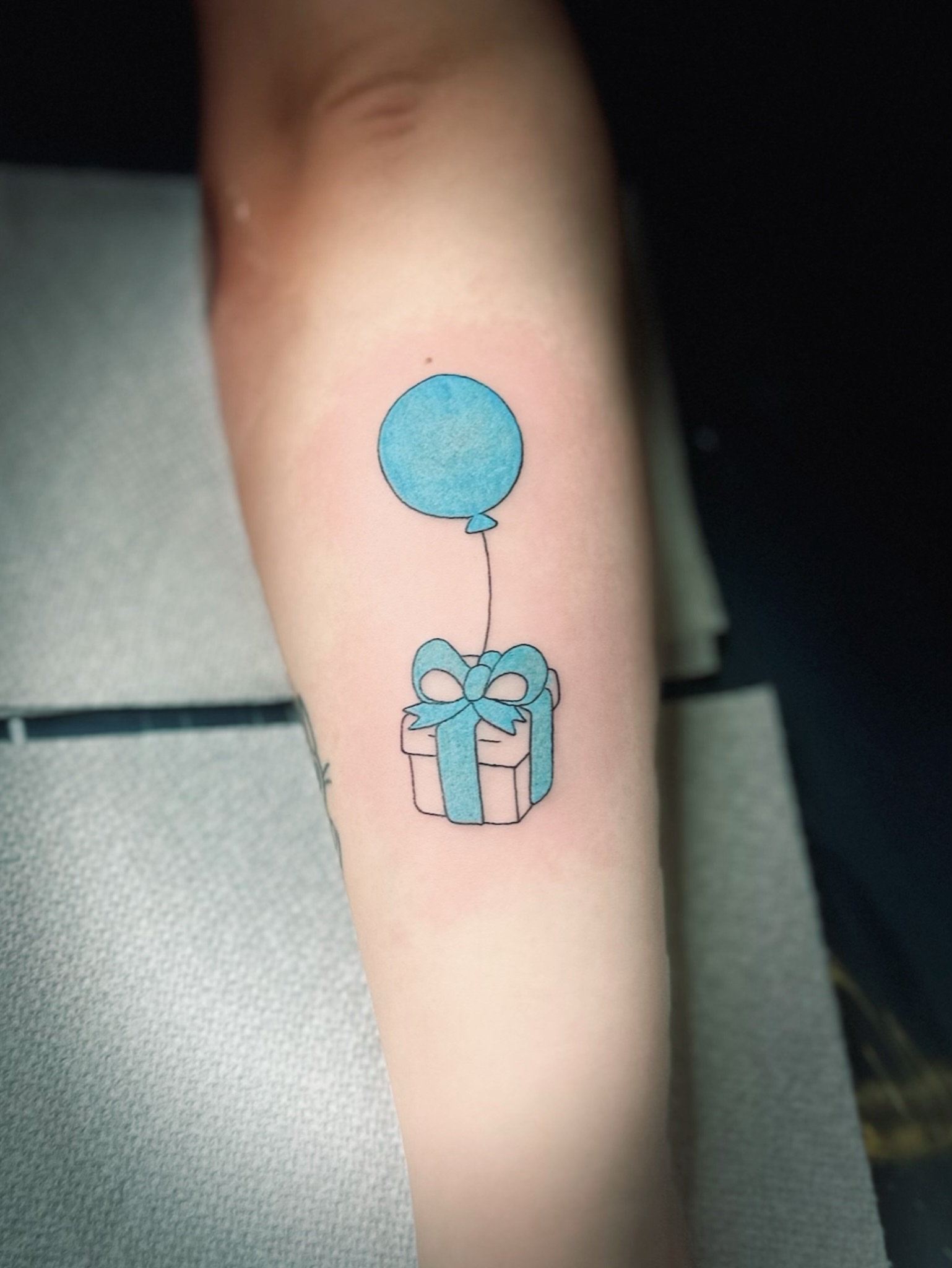 Balloon and gift box minimalist tattoo on the forearm by NuNu