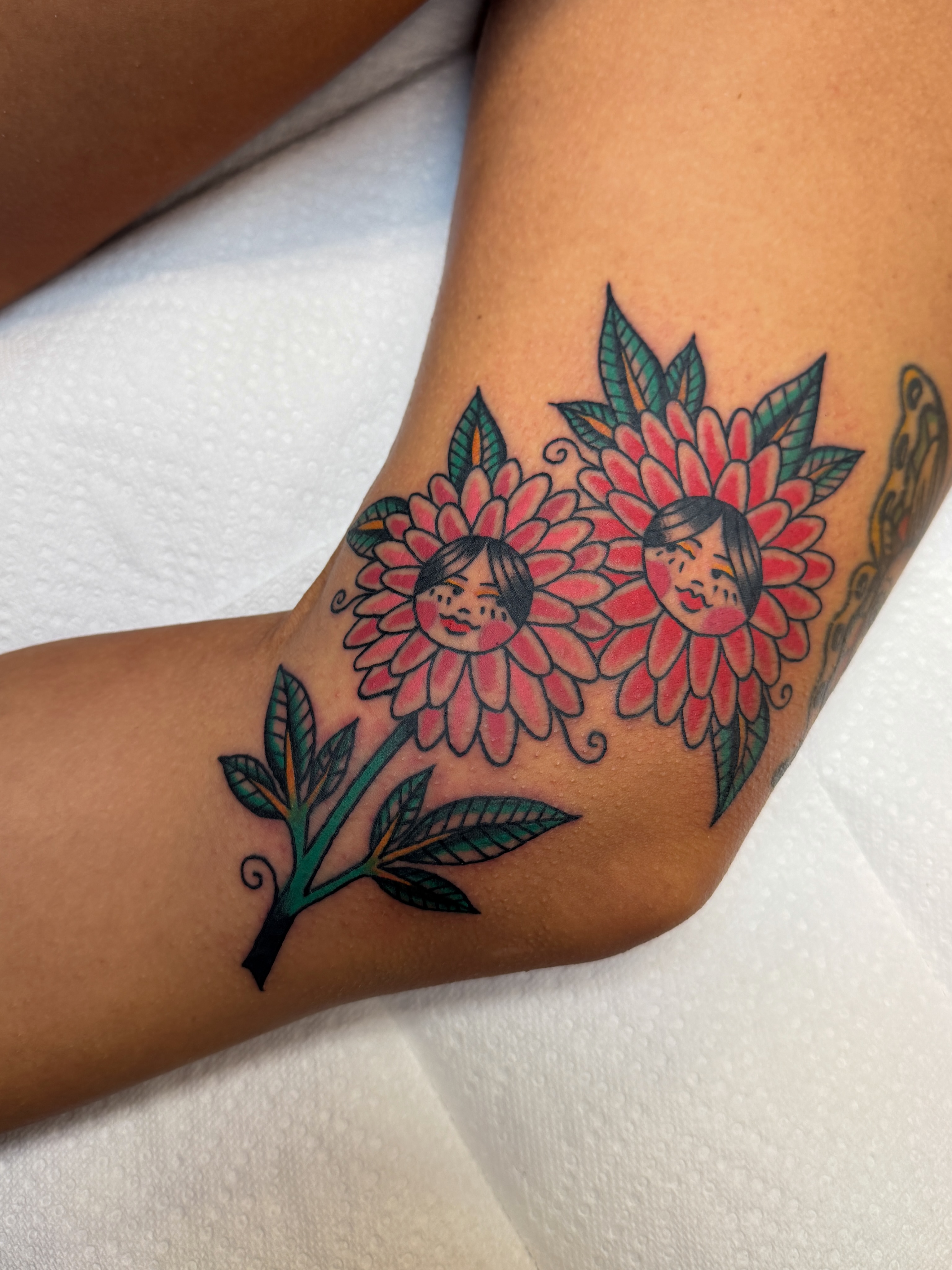 Flower faces American traditional tattoo on the forearm by Hannah Eddy