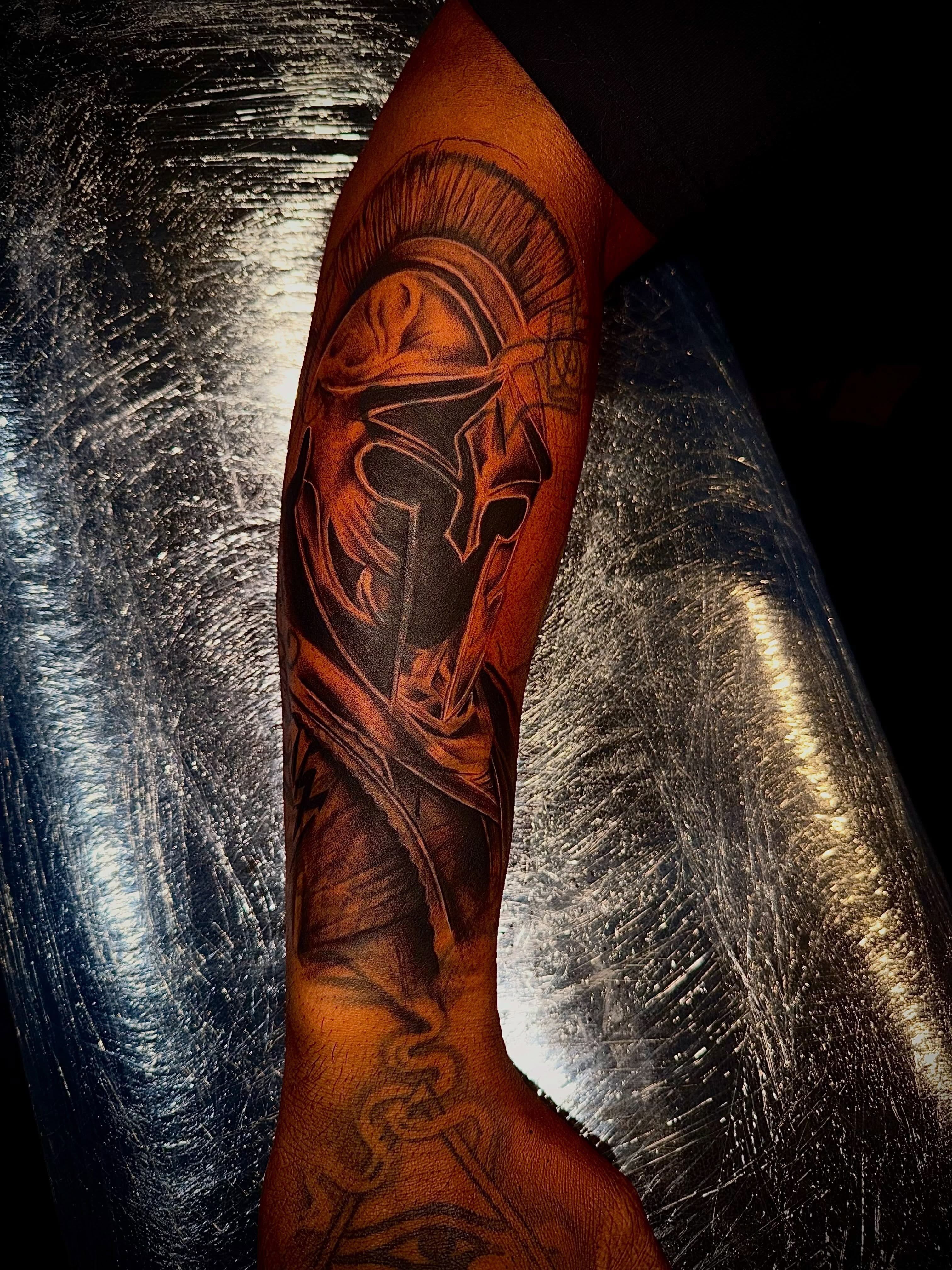 Spartan helmet black and grey tattoo on the forearm by Clifford Jordan