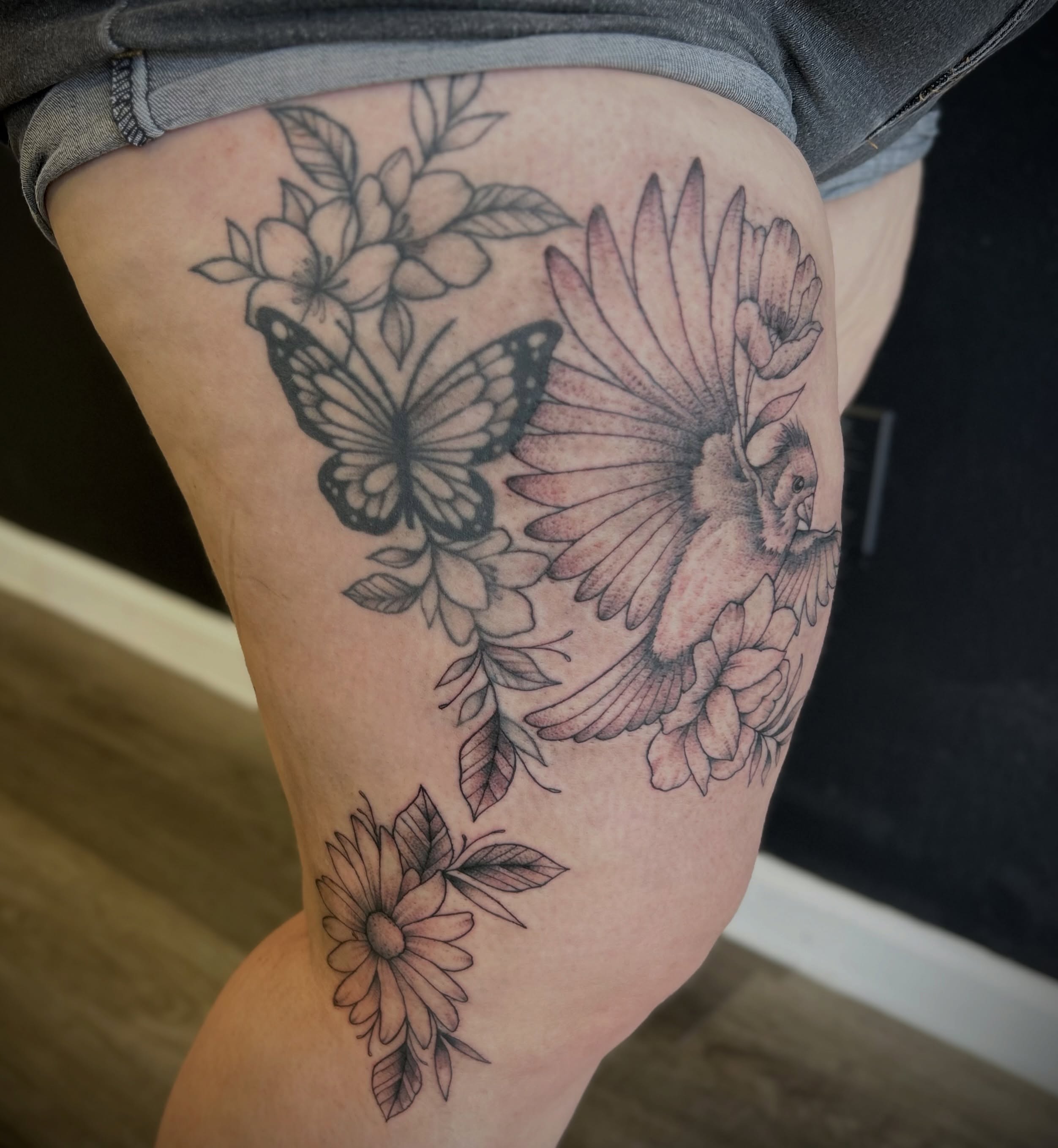 Flowers and butterfly black and grey tattoo on the thigh by Browtique & Ink, Clearwater, Florida