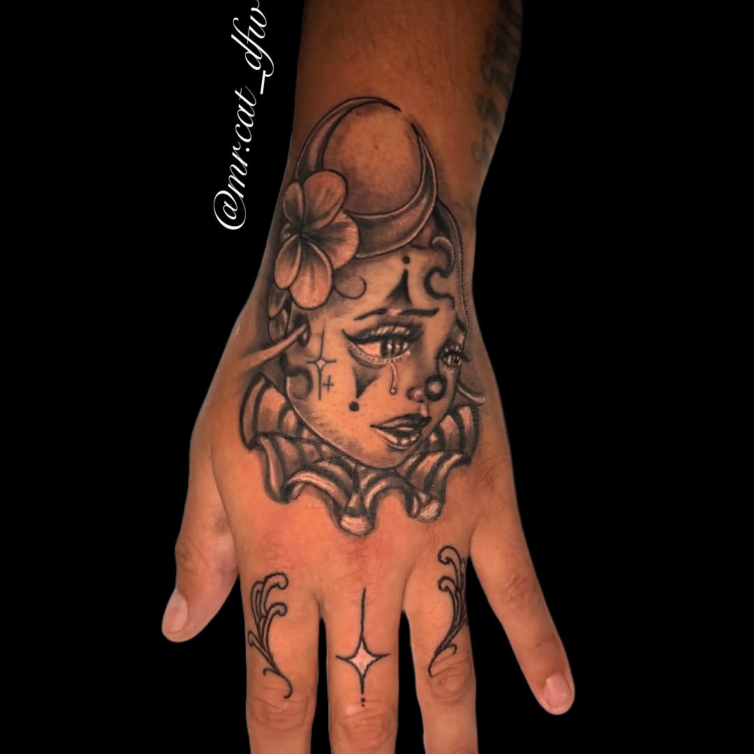 Clown face black and grey tattoo on the hand by Junior Sanchez Dfw