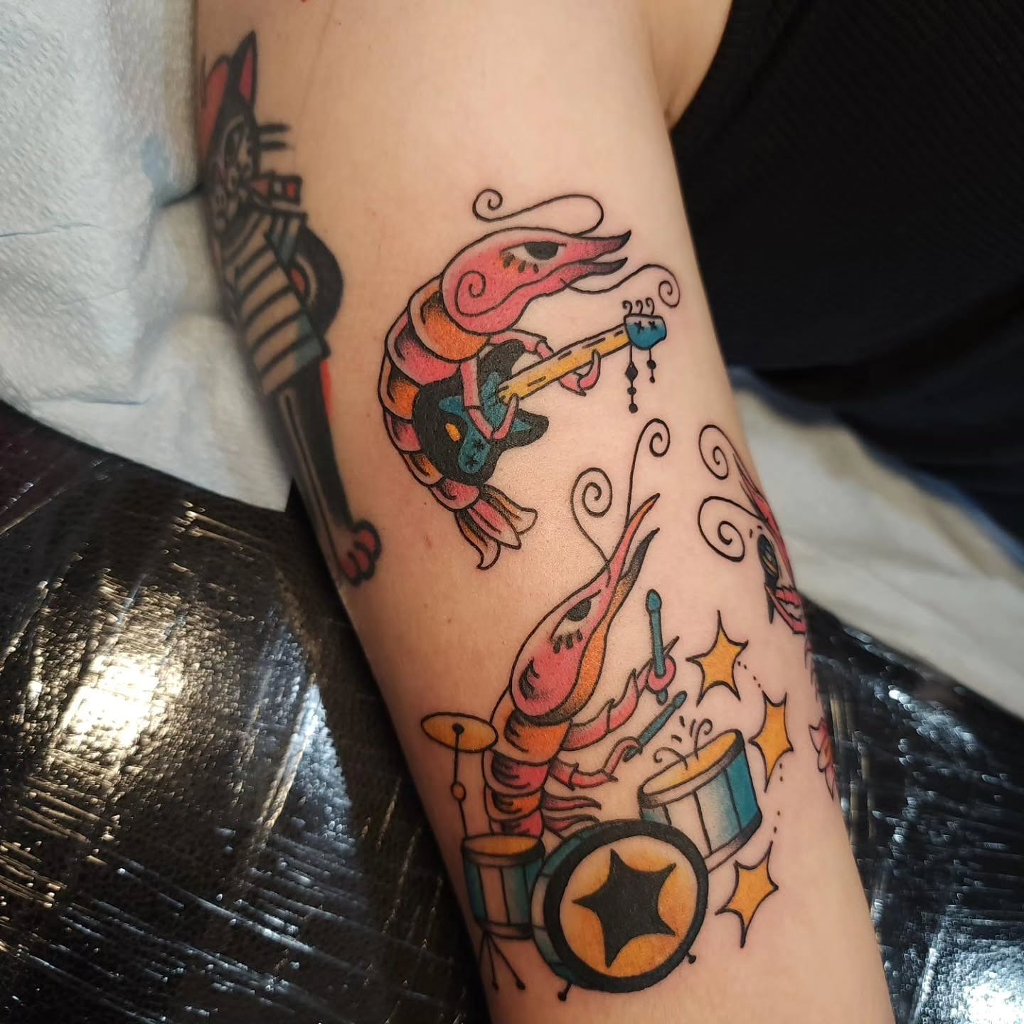 Shrimp playing instruments American traditional tattoo on the forearm by Maxine Stewart