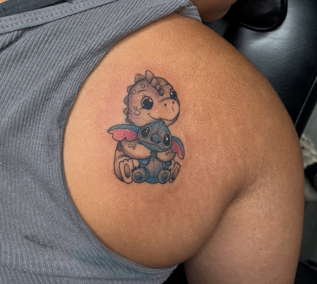 Stitch and dinosaur dotwork tattoo on the shoulder by Tattoos by Hailey