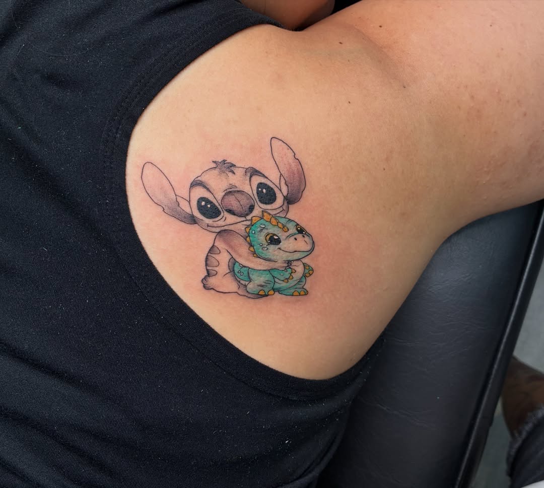Stitch and dinosaur dotwork tattoo on the shoulder by Tattoos by Hailey