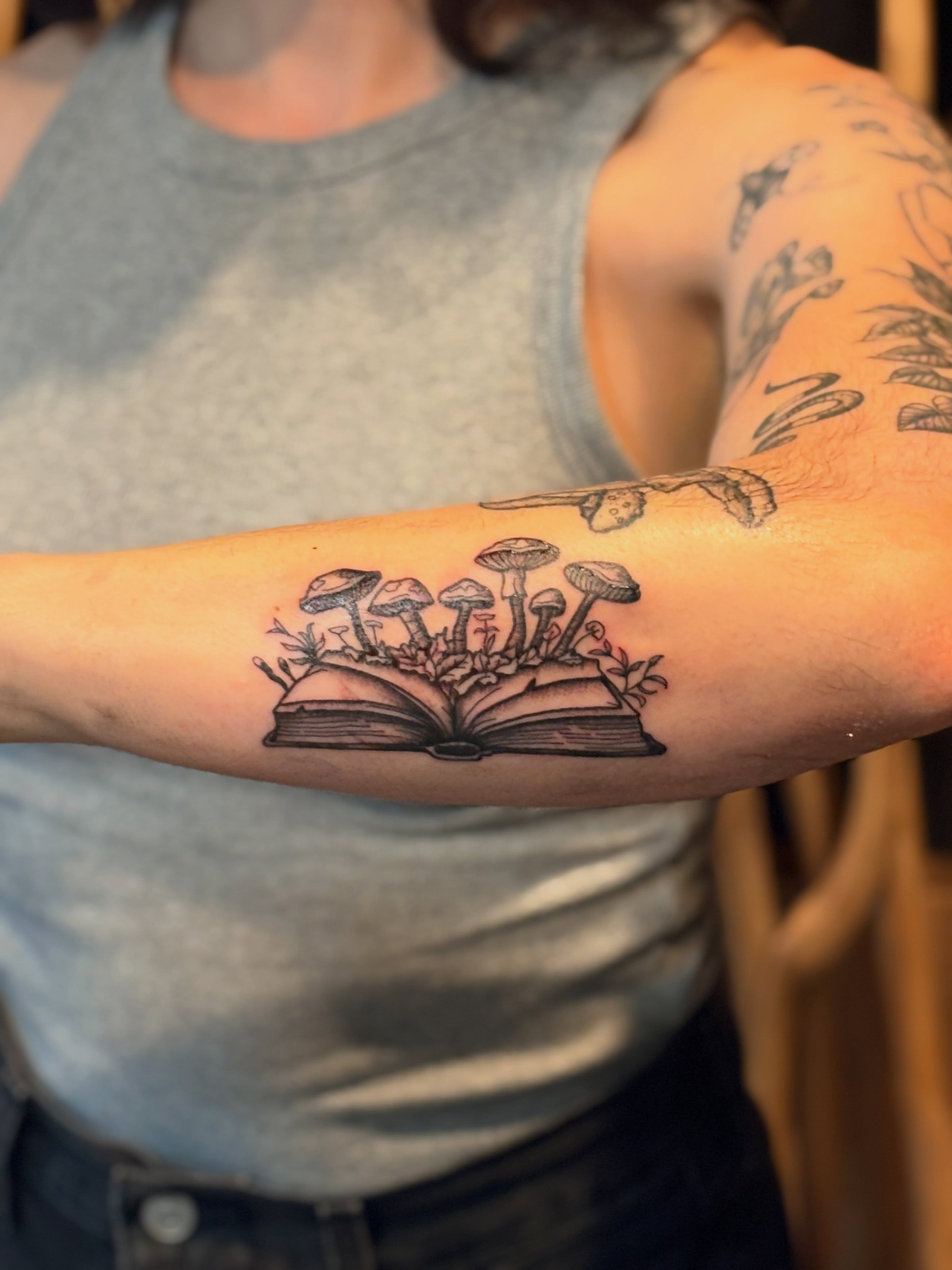 Book with mushrooms black and grey tattoo on the forearm by CJ