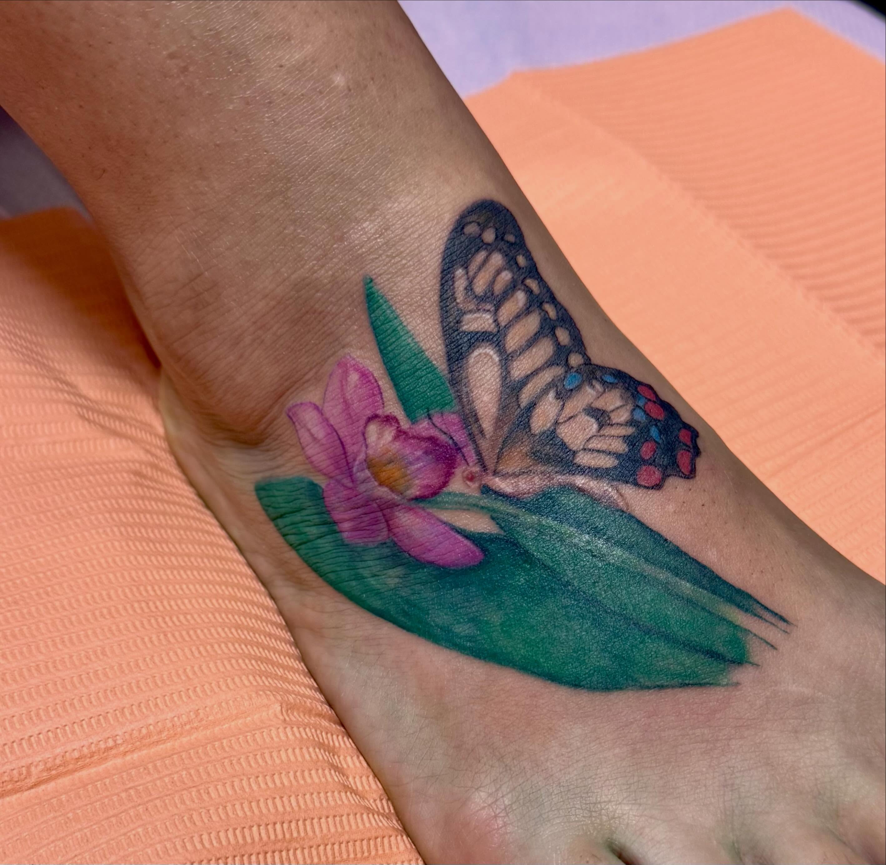 Butterfly and lotus watercolor tattoo on the foot by Enda 🧚🏻‍♀️